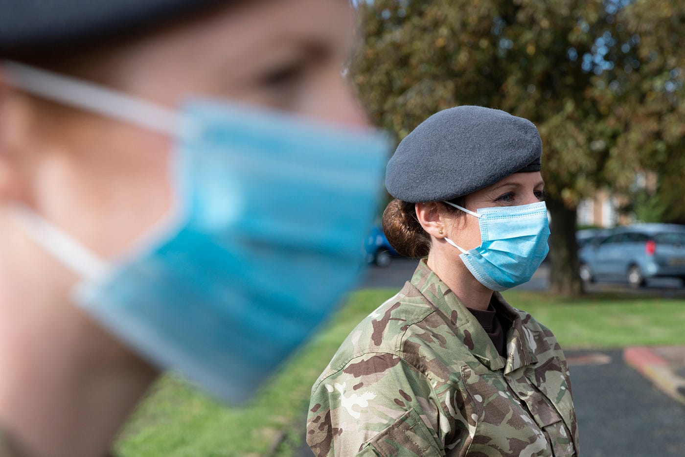 Two members of the RAF in combats are pictured in profile wearing PPE facemasks