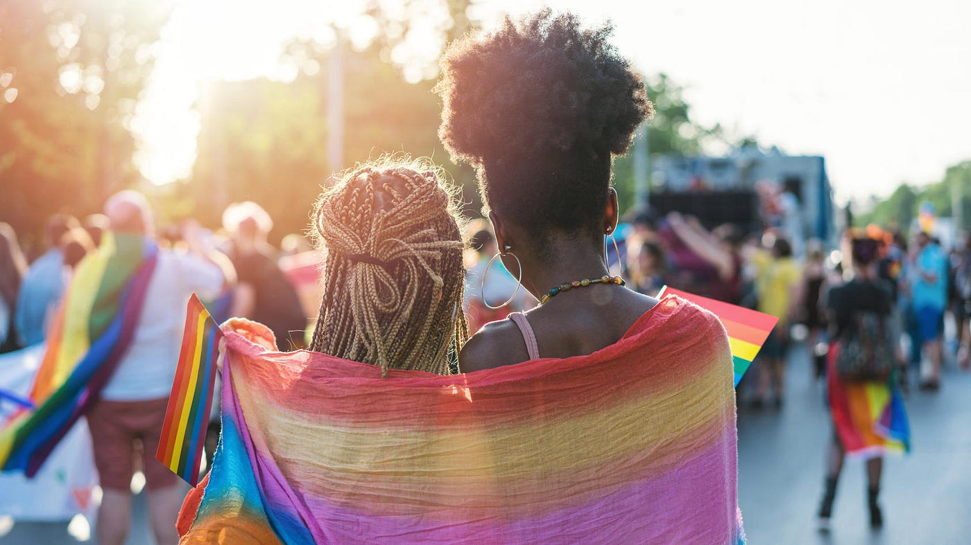 two women wrapped in a pride flag