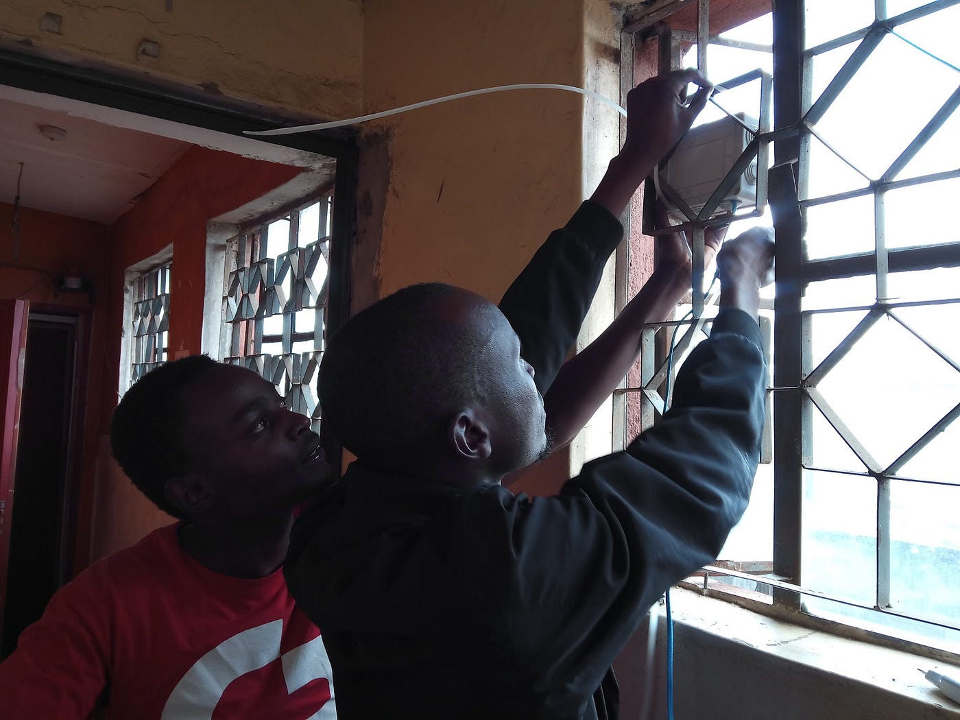 Two people install an air quality sensor on a window.