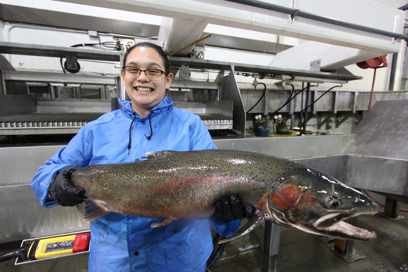 AmeriCorps member Kylee shows off a smile and a huge salmon