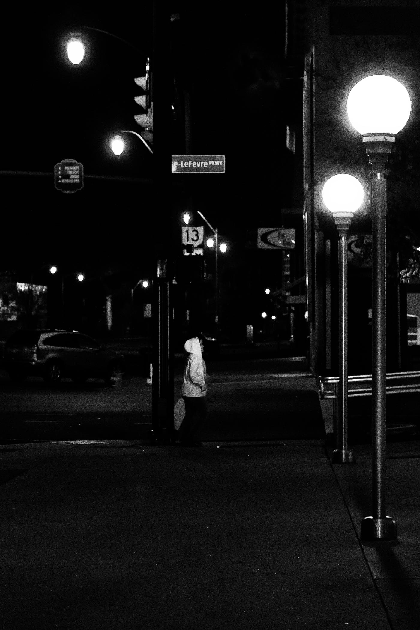 13 lights in the shot of a person walking at night.