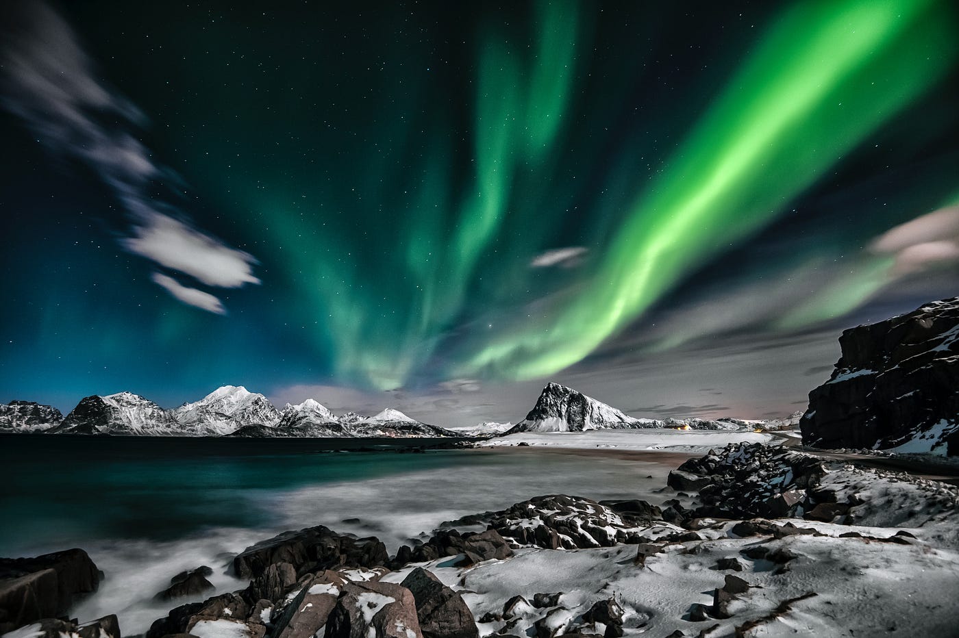 The Northern Lights with a body of water and mountains in the background