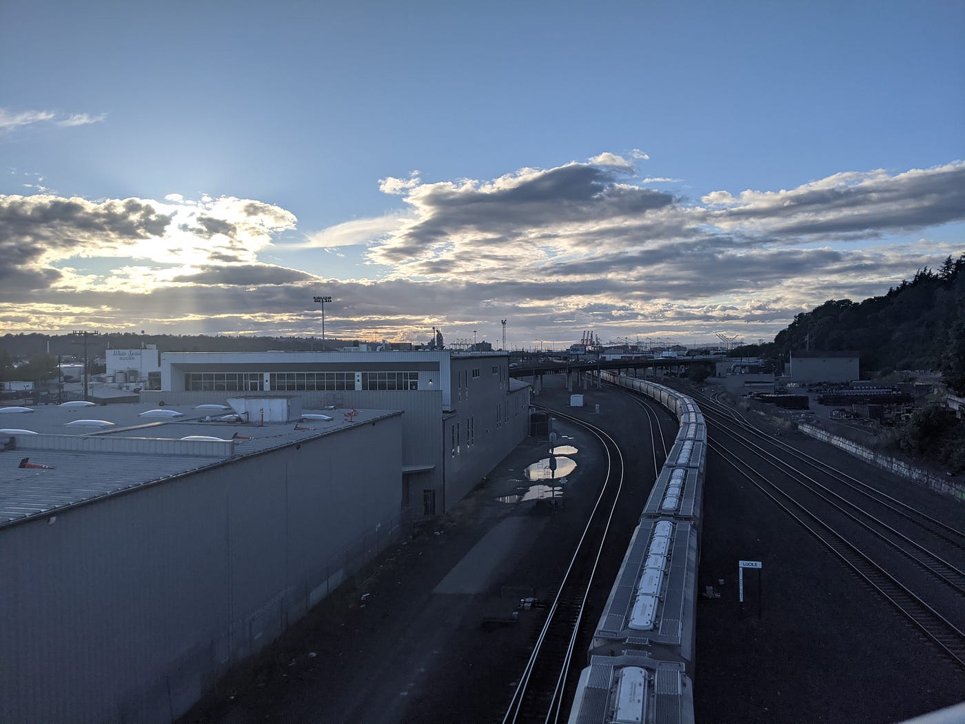 A sunset over an industrial area with a train passing through.