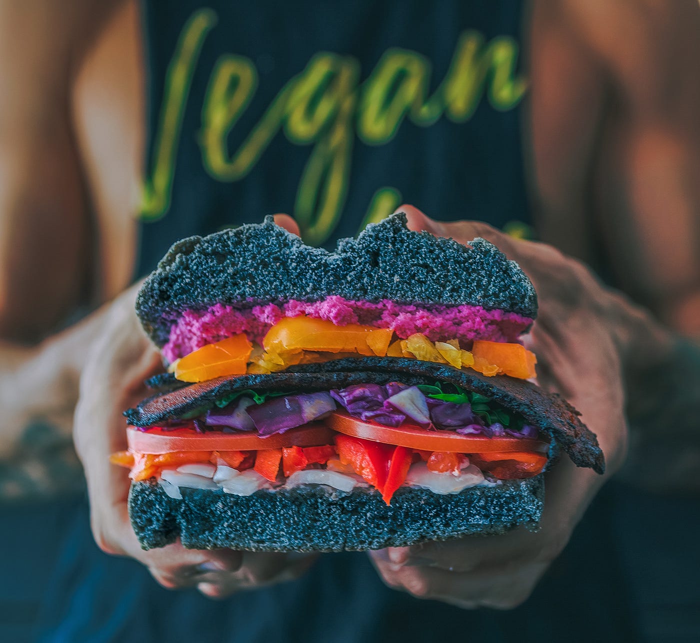 A sandwich with somewearing a t-shirt with the word vegan on it in the background.