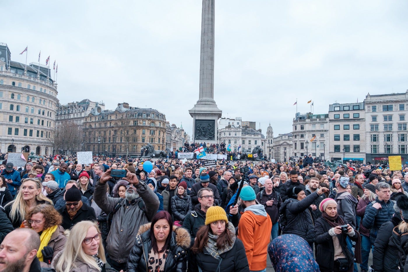 Een mensenmassa op Trafalgar Square in Londen. De mensen protesteren tegen coronamaatregelen. Sommigen houden een protestbord omhoog. Niemand draagt een mondkapje. In de achtergrond staat Nelson’s Column.