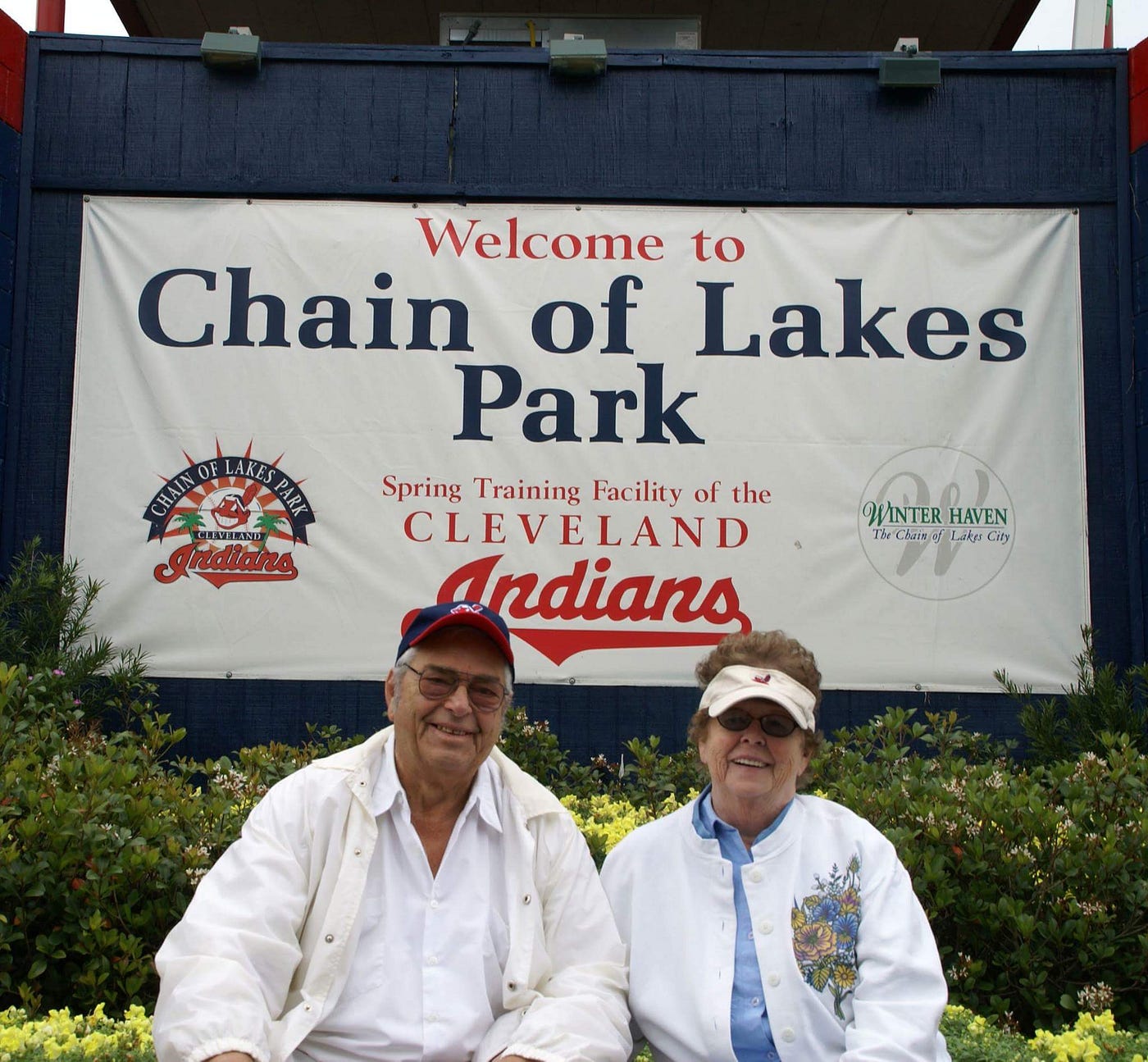 2 people sitting in front of a Cleveland Indians sign