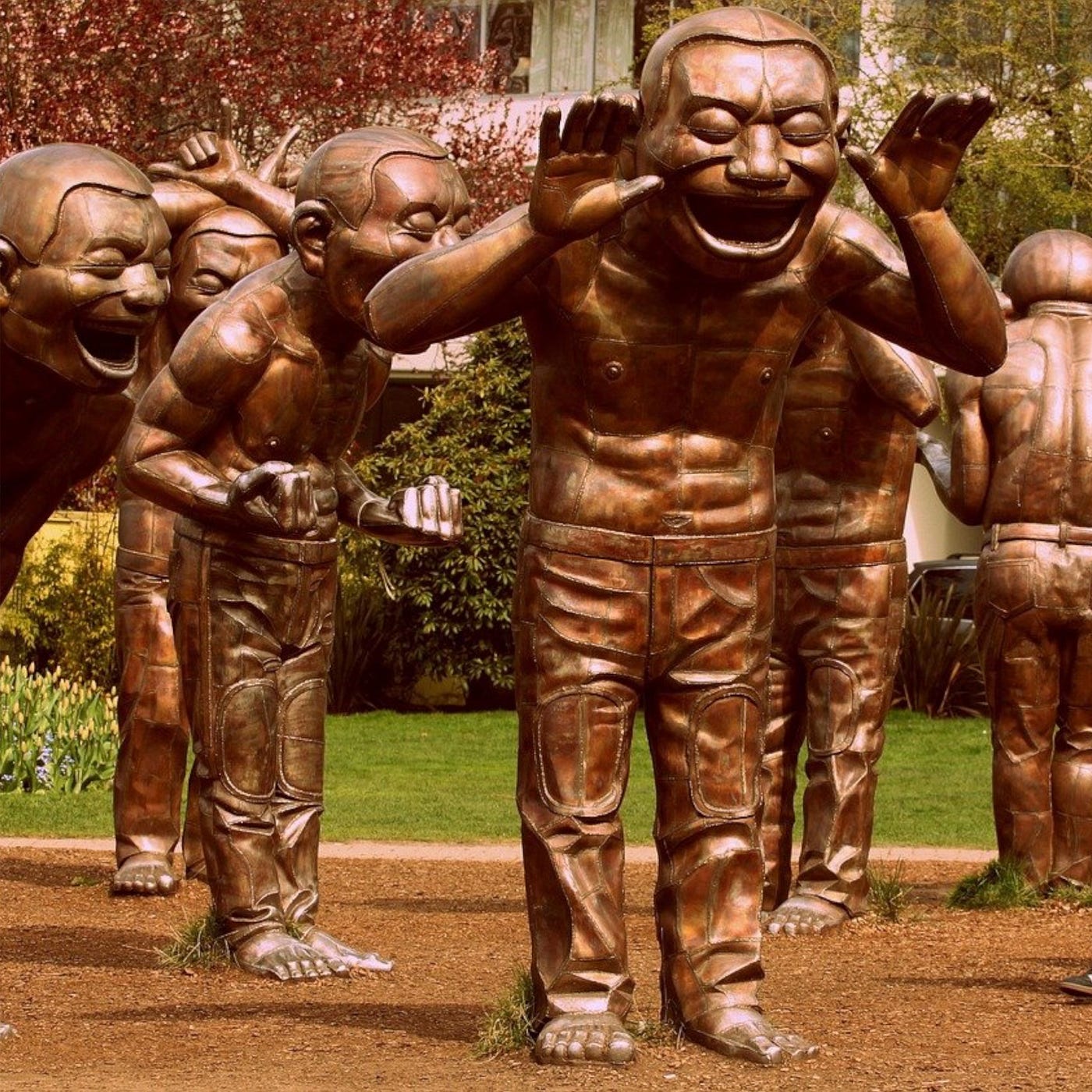 Color photo of “A-maze-ing Laughter”, a 2009 bronze sculpture of a large group of larger than life, laughing bronze men in various poses, by Yue Minjun, located in Morton Park in Vancouver, British Columbia, Canada.