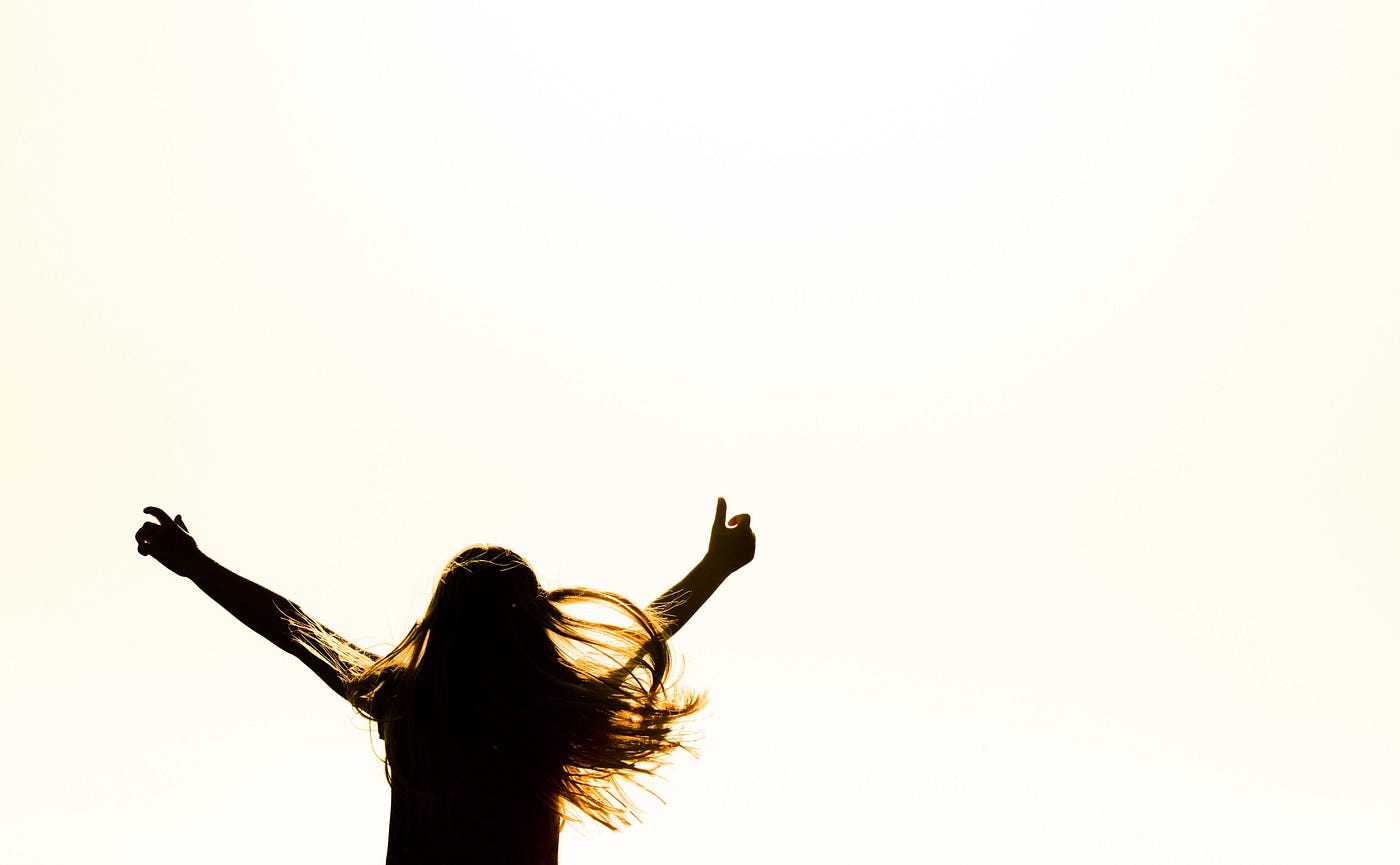 The back of a woman with her thumb up raising her arms in celebration