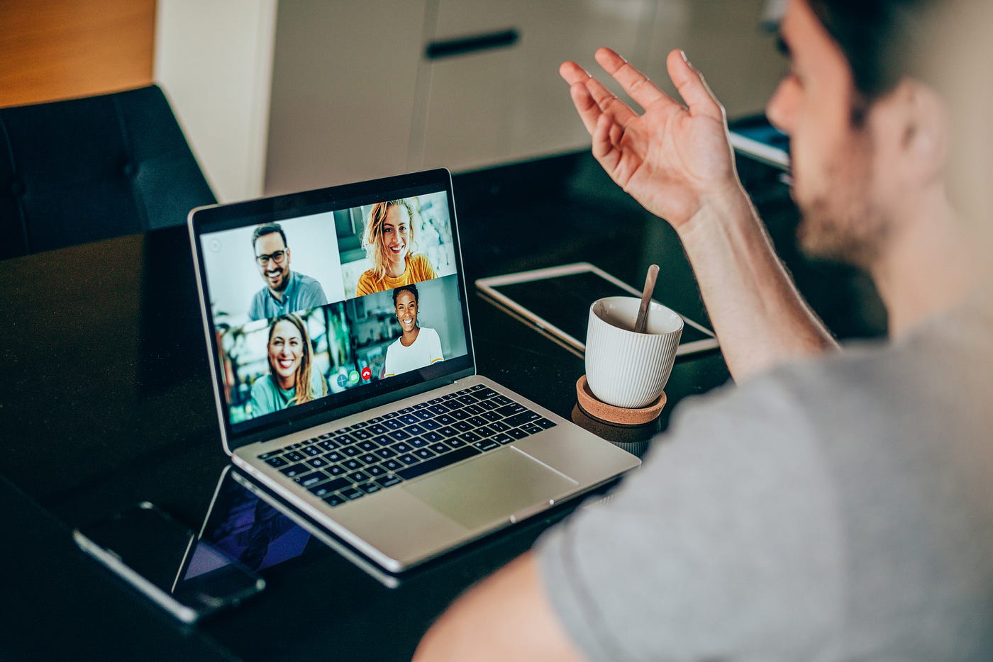 A young man talking to his friends on an online video call from his laptop.