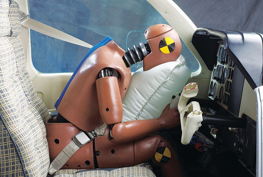A crash dummy hitting a seatbelt airbag during a text in a small airplane.