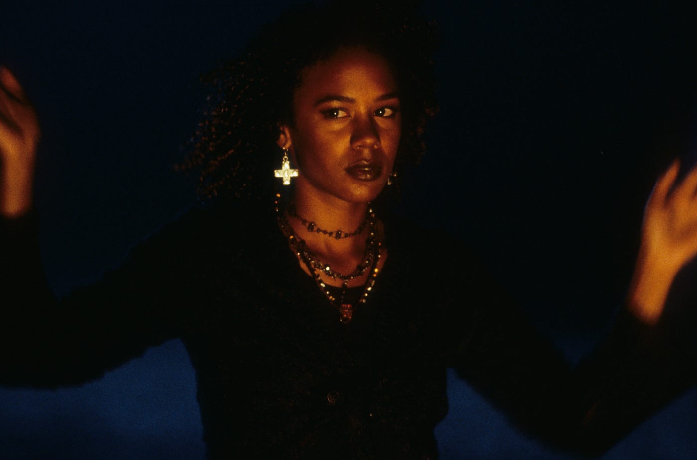 Screenshot of Rachel True from “The Craft.” She is wearing black and many necklaces.