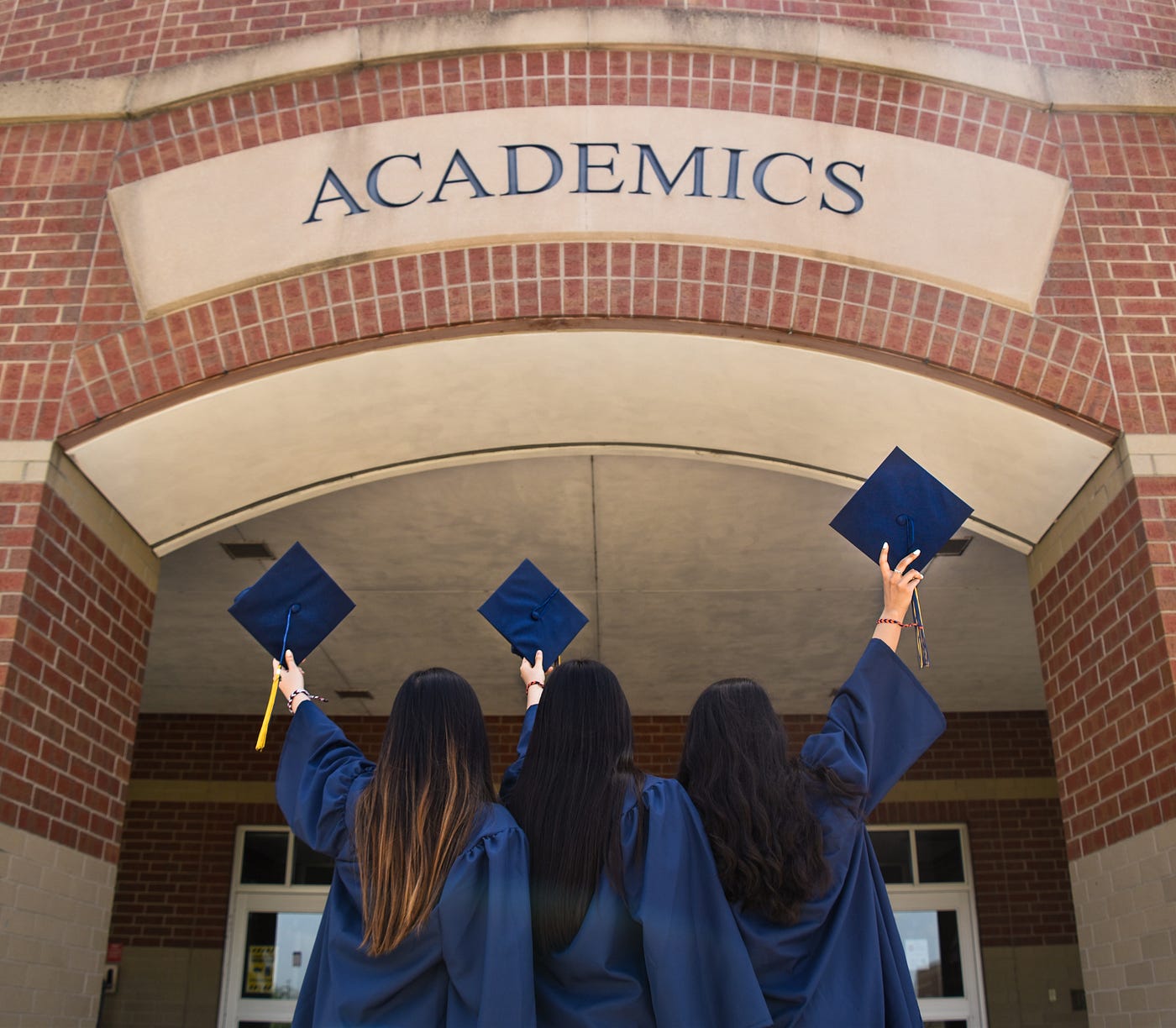 three people just graduated and stand in front of their university with their graduation attire