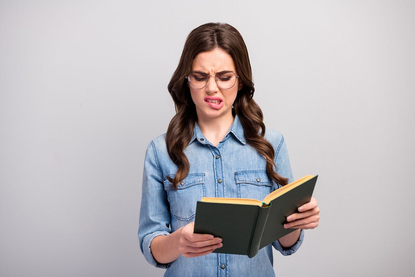 Woman reading a book and making a silly face.