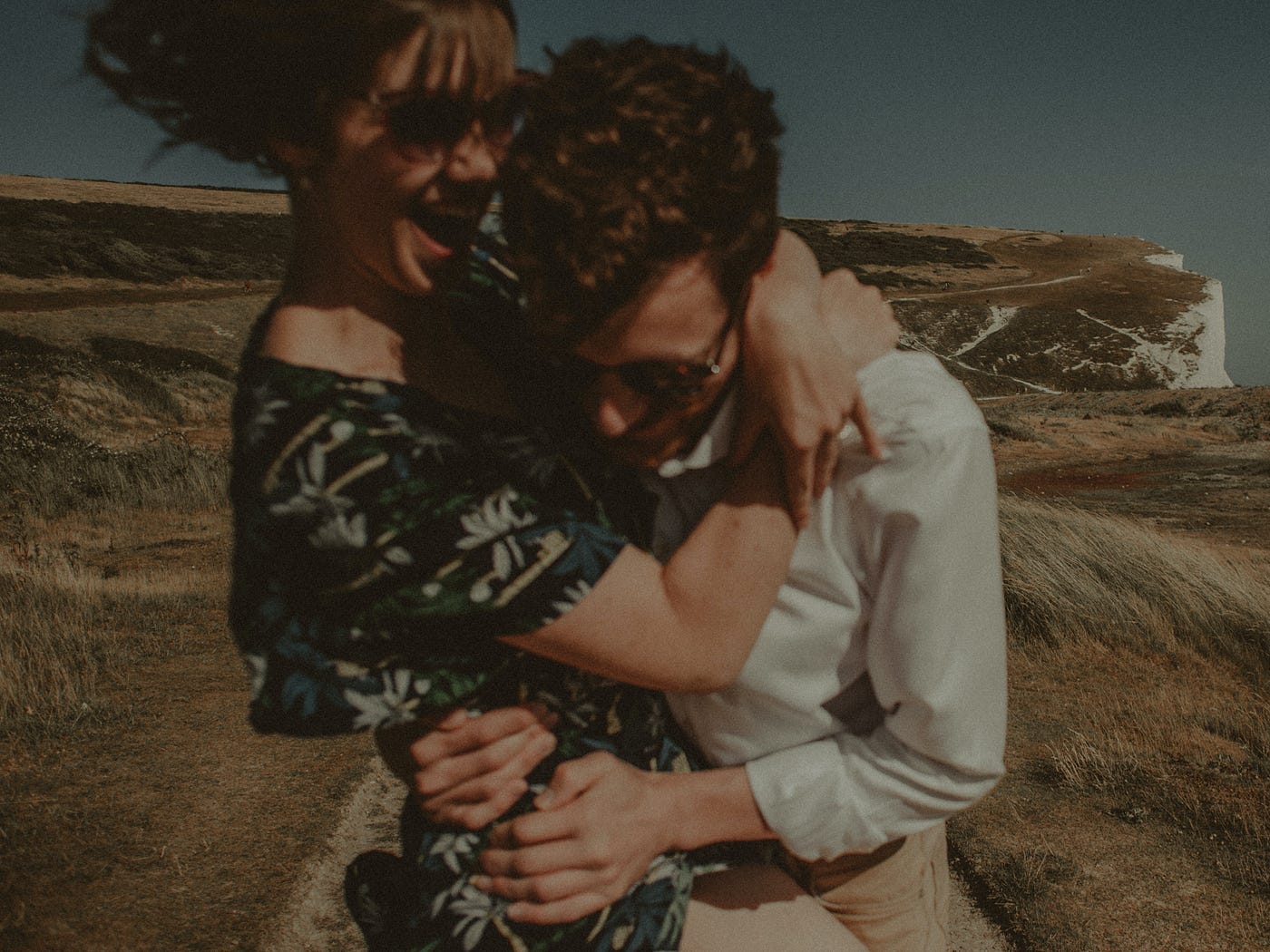 A happy couple embraces in a grassy field