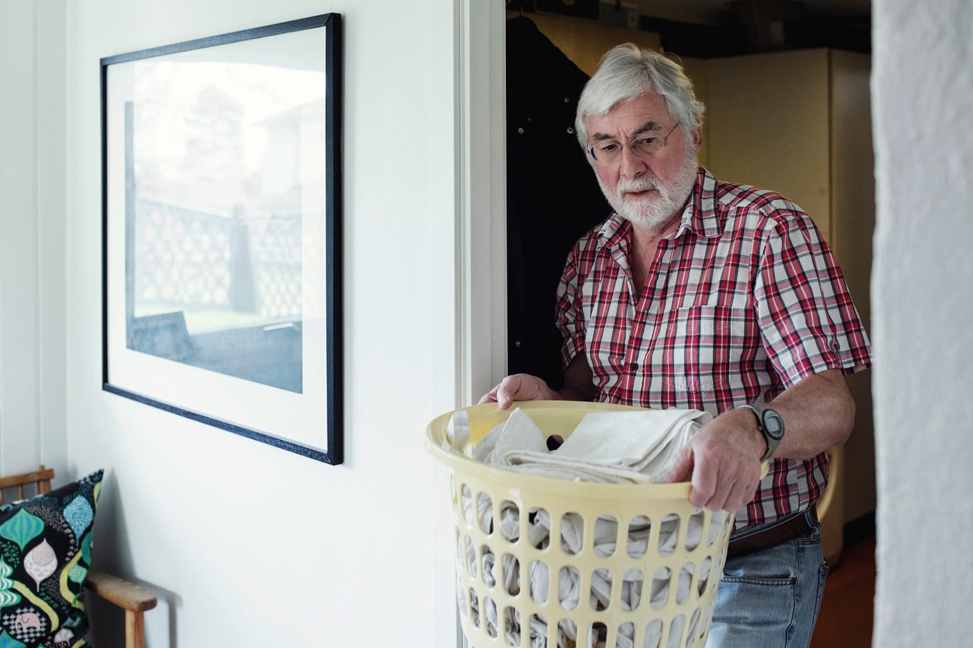 A man holding laundry basket while walking through doorway at home