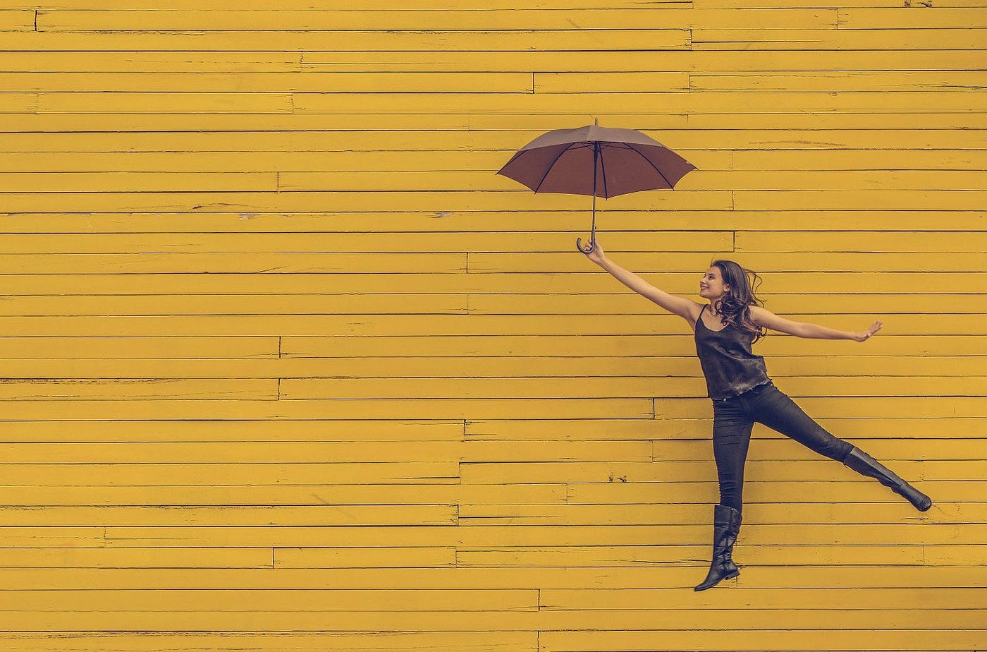 woman with umbrella in front of wall
