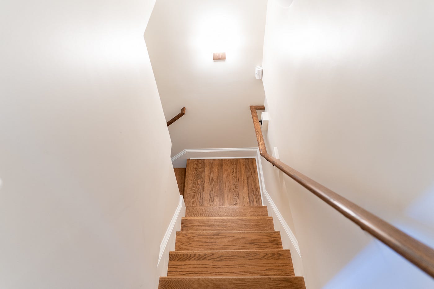 Staircase that has been renovated to create more head room, and is complimented by walnut wood floors and railing.