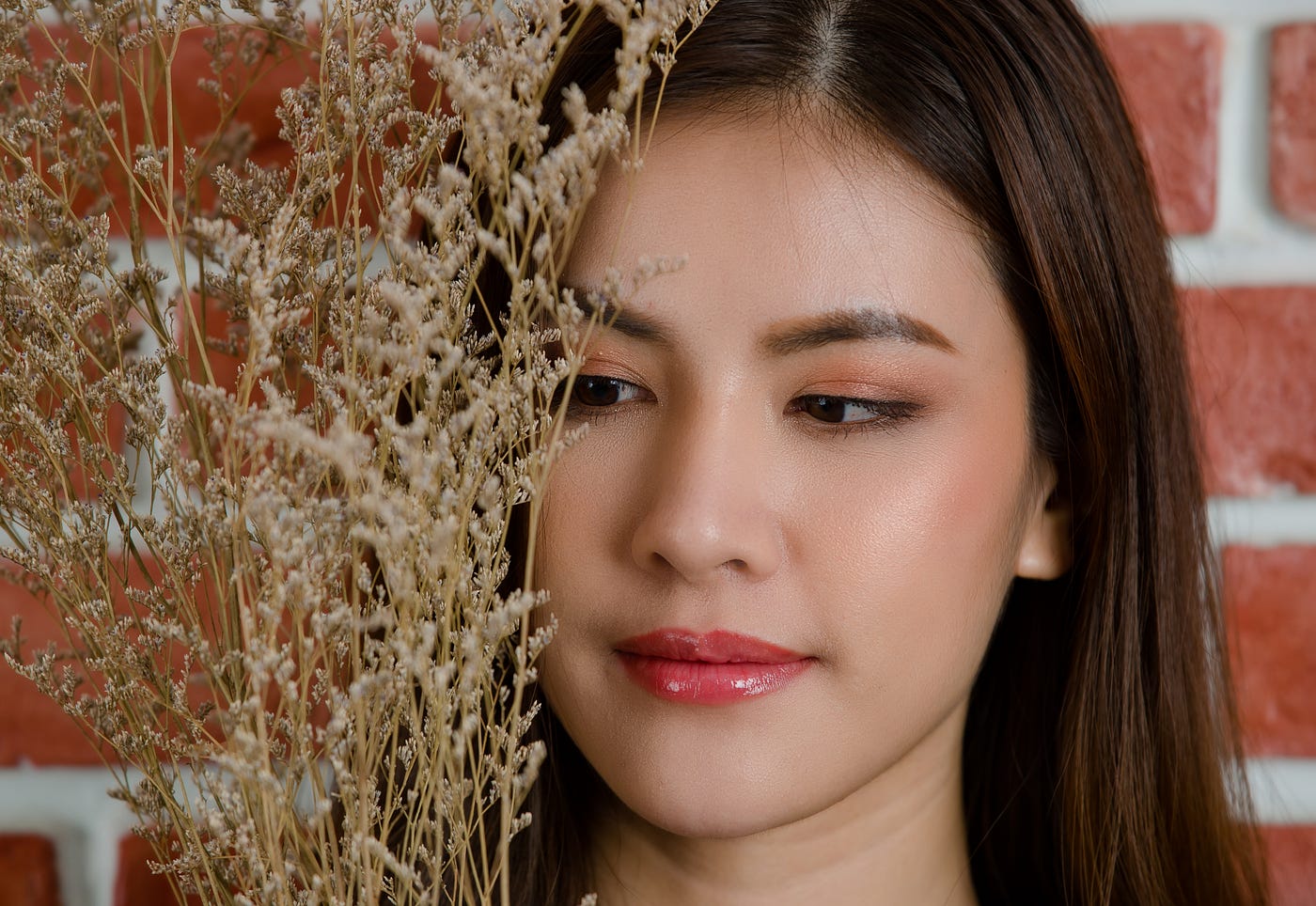 close-up-young-beautiful-attractive-asian-female-model-s-face-with-flower-s-branch-against-orange-brick-wall-background — Un Swede
