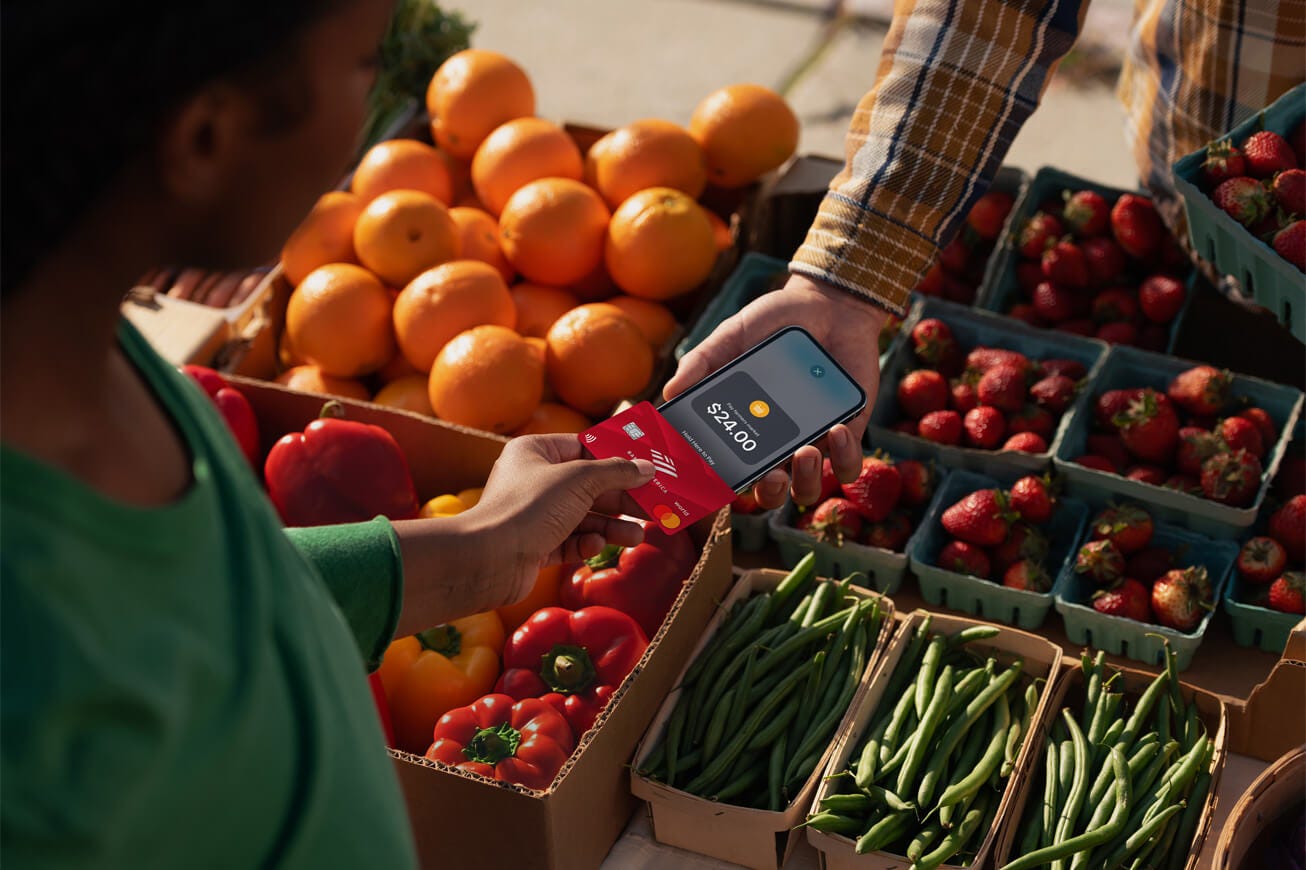 A customer uses Tay to Pay on iPhone to buy fruit at the farmer’s market.