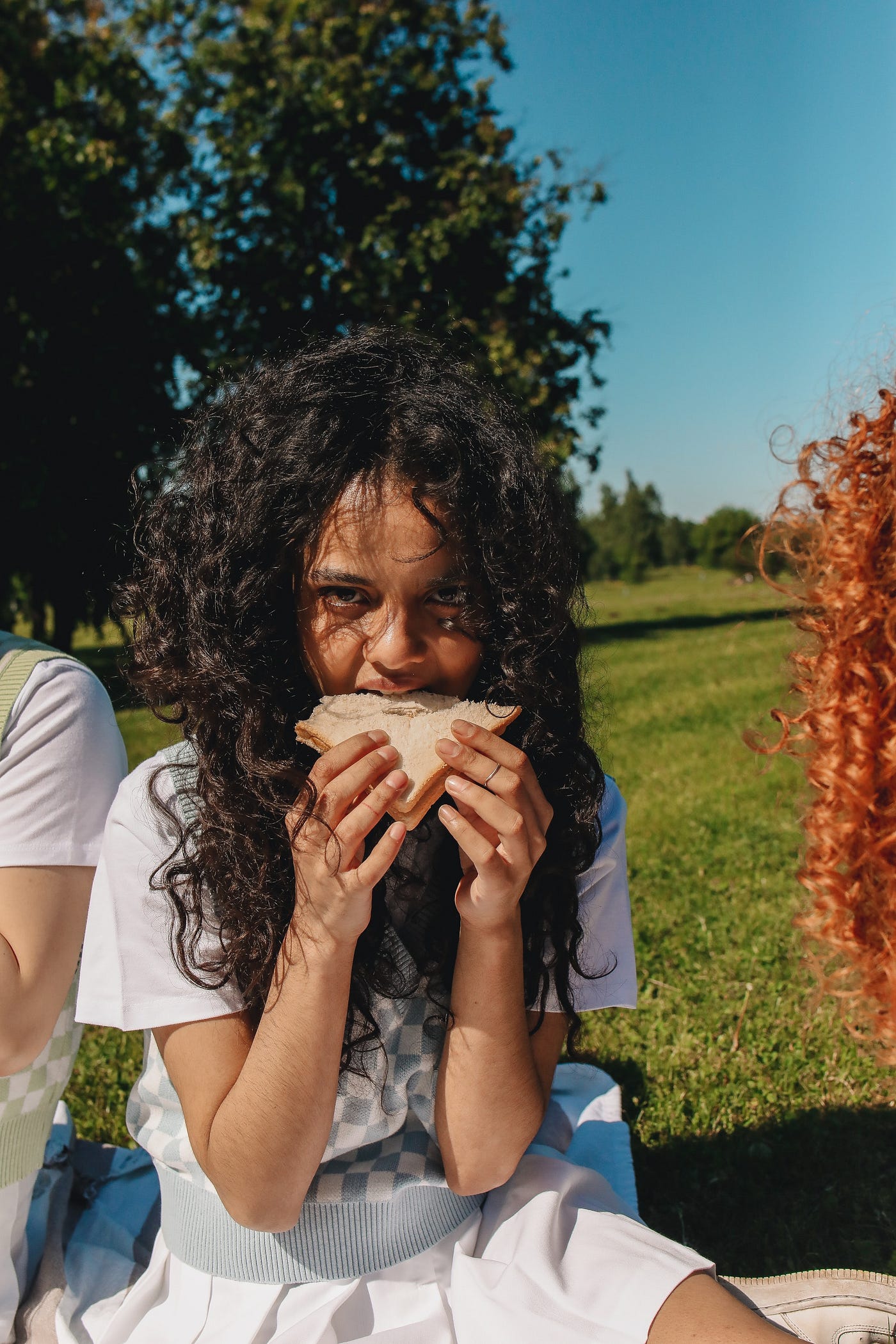 Young woman eating a sandwich in the sunshine.