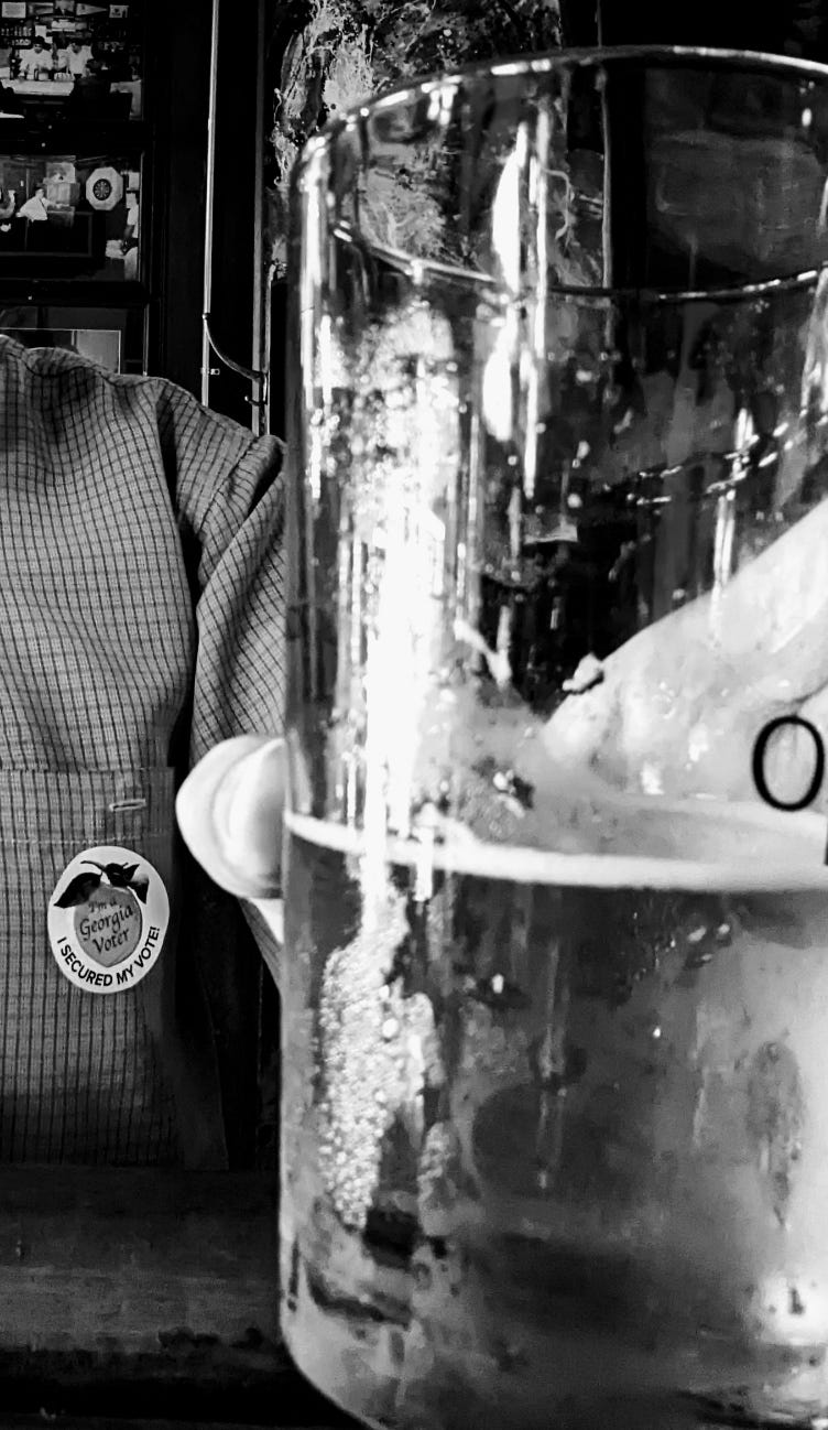 An I’m a Georgia Voter sticker on a shirt behind a glass of beer.