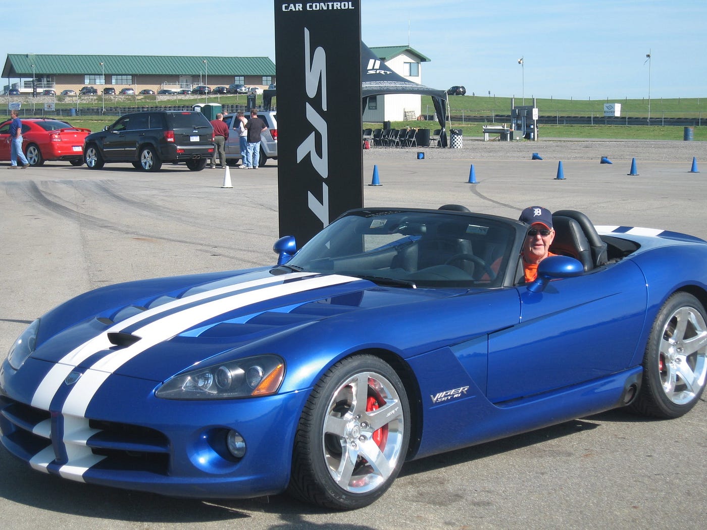 Man in driver’s seat of a blue Dodge Viper with white racing stripes.