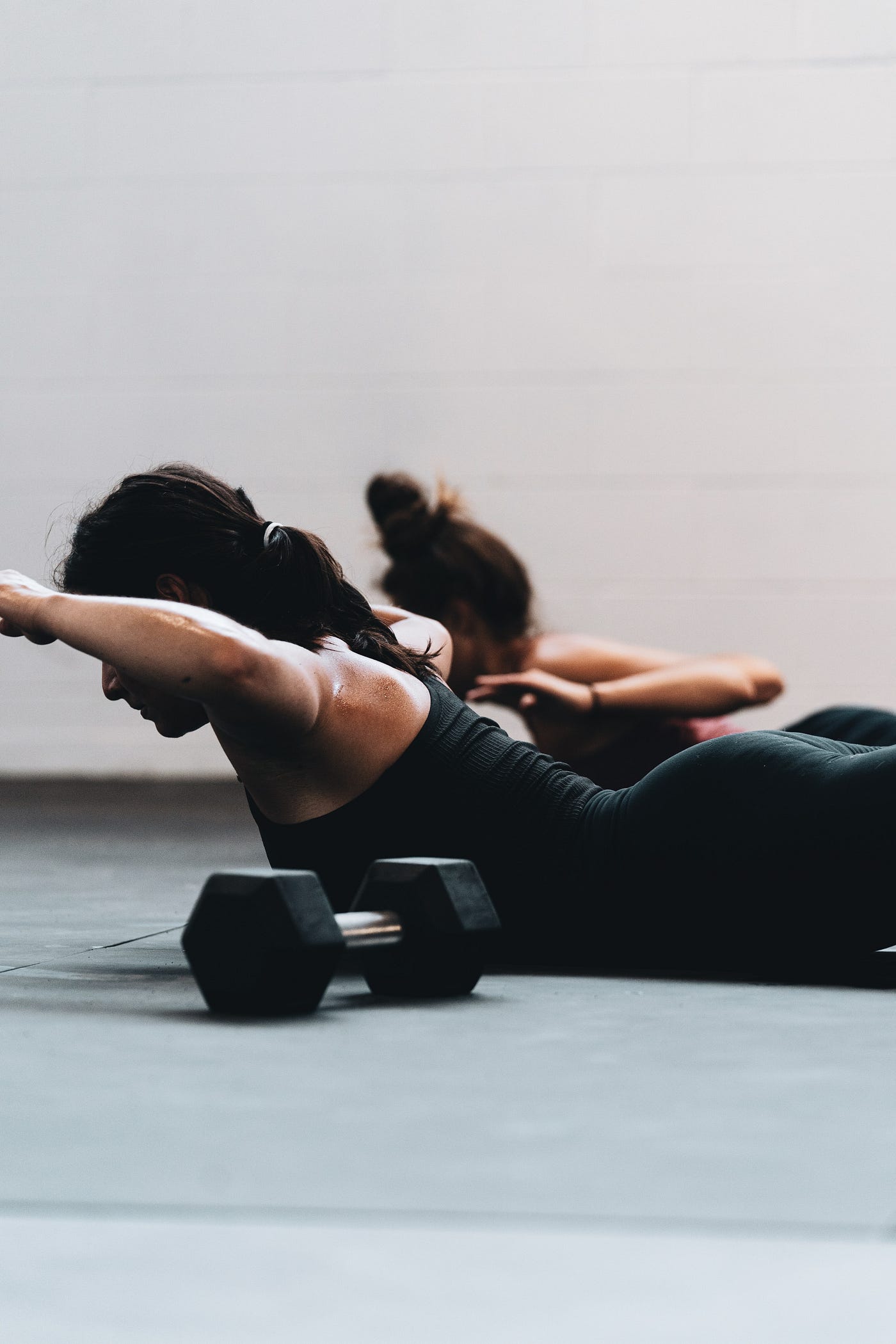 A woman, face down, lifting her arms, head, and chest off the floor to help train her mid and lower back muscles.