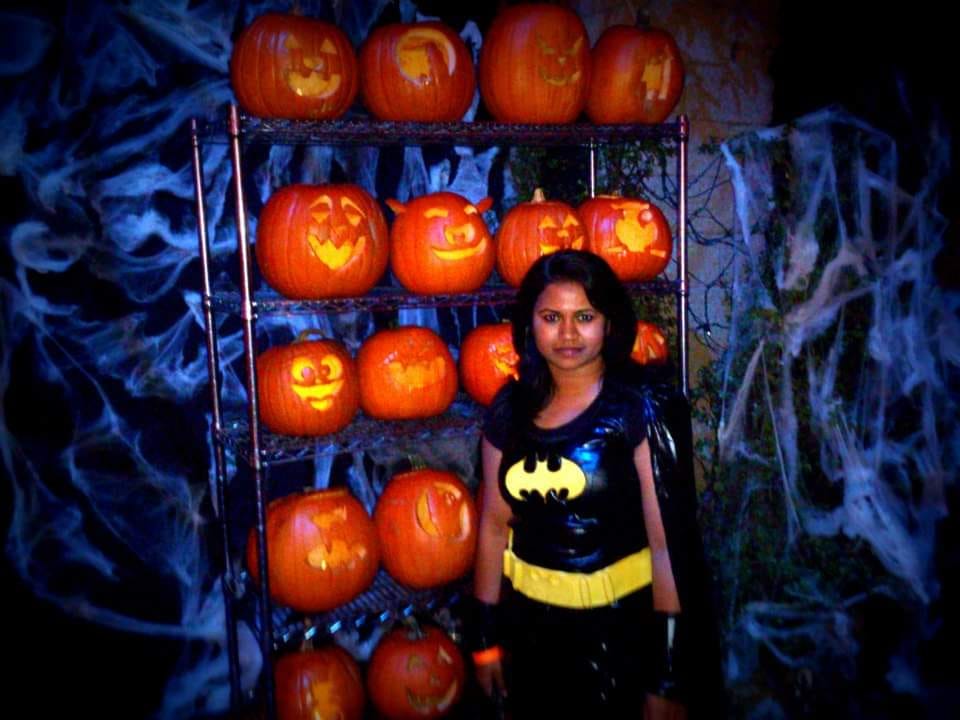 Tamil wearing a Batman T-shirt, standing in front of Hallowe’en jack-o-lanterns
