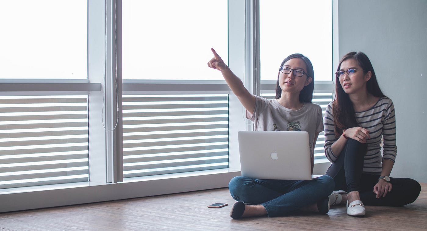 Two women by a laptop brainstorming