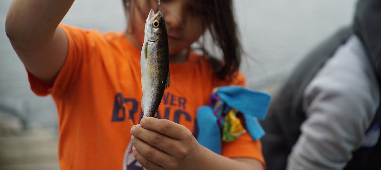 girl holding a small fish