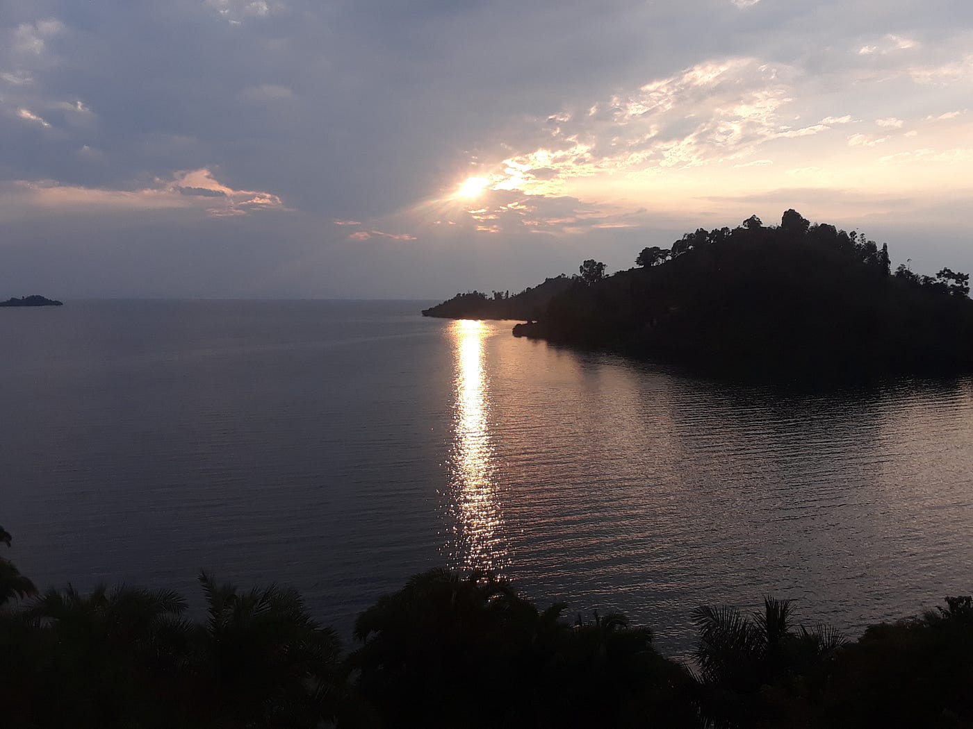 An image of a lake at dusk with a green island forest visible in the distance.