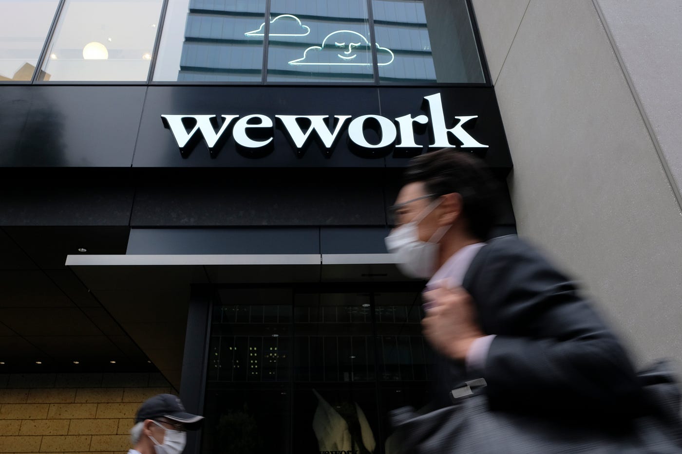 A man wearing a face mask walks past the front of a WeWork building in Tokyo.