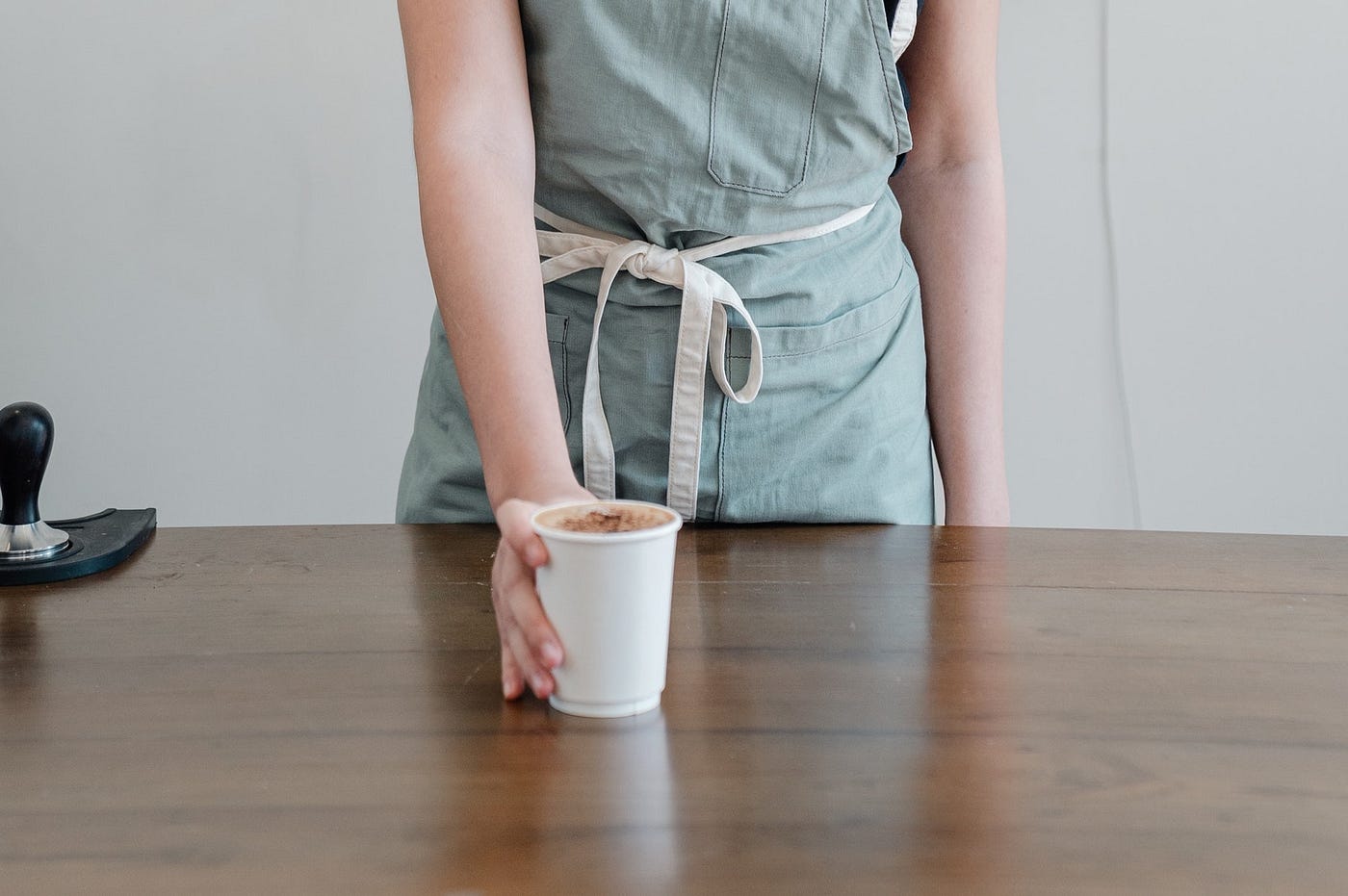 A woman serving a cup of coffee across a counter