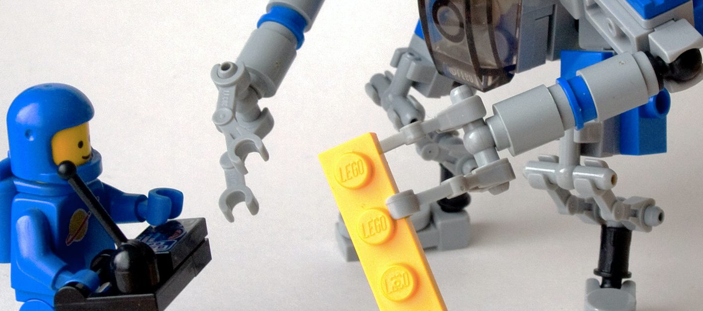 A Lego astronaut remote-controlling a Lego robot