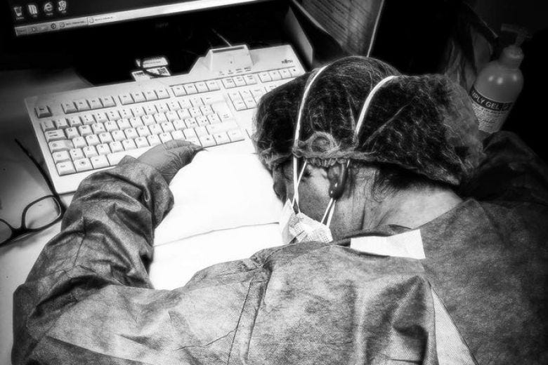 Exhausted nurse falls asleep in front of her computer.
