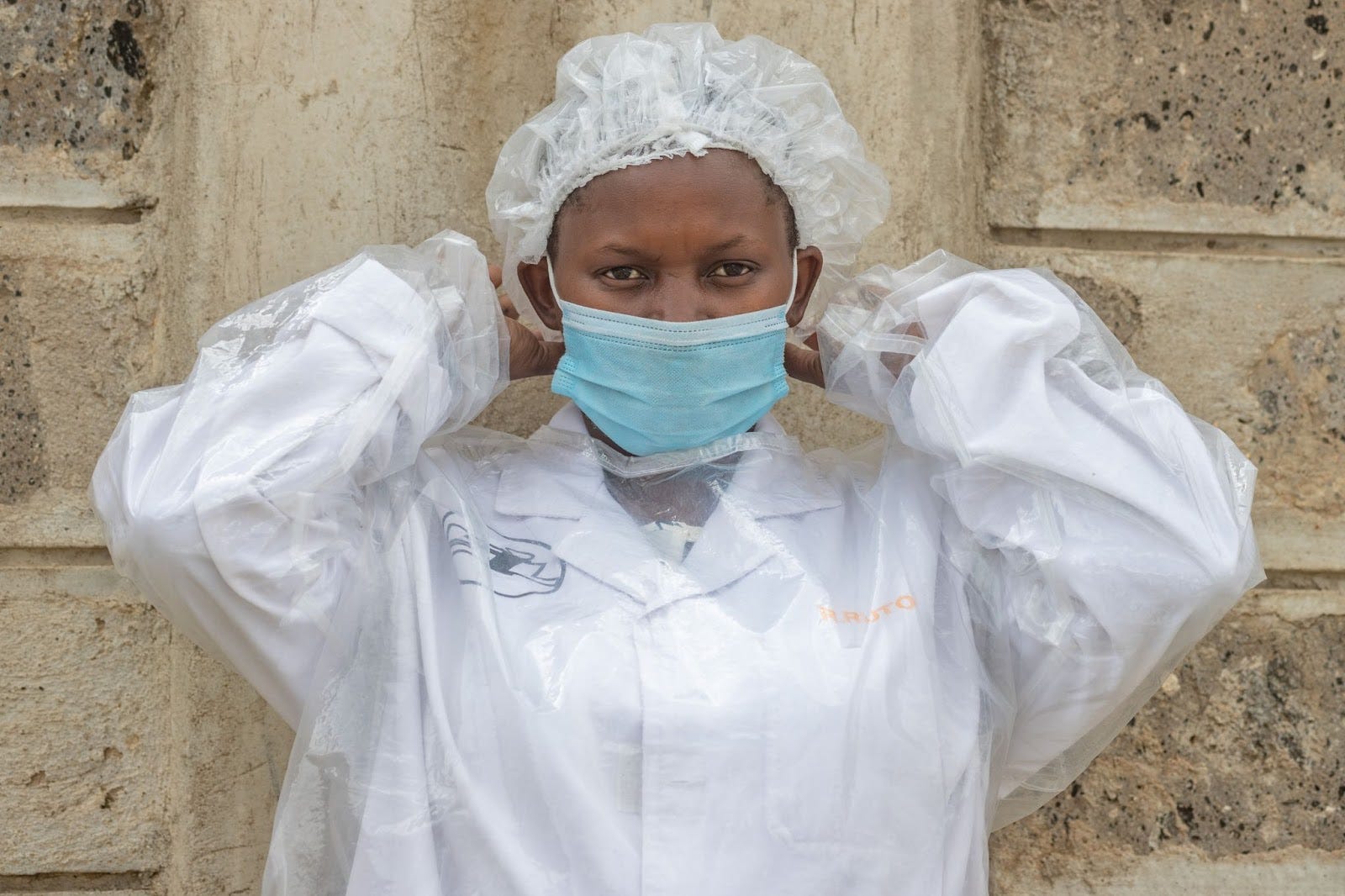 A SilAfrica team member wearing PPE gown and putting on a mask