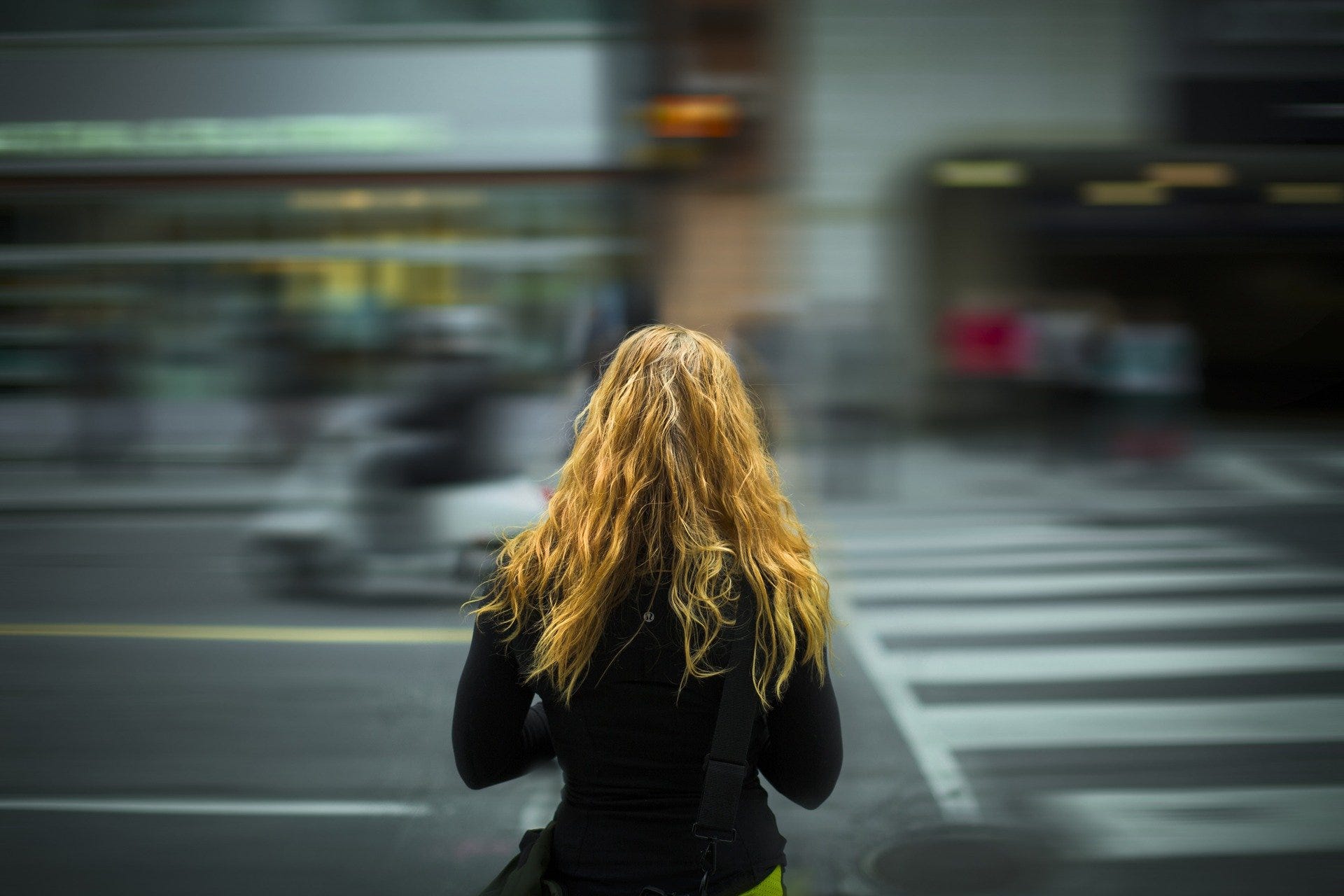 Woman standing and waiting at a level crossing in the street