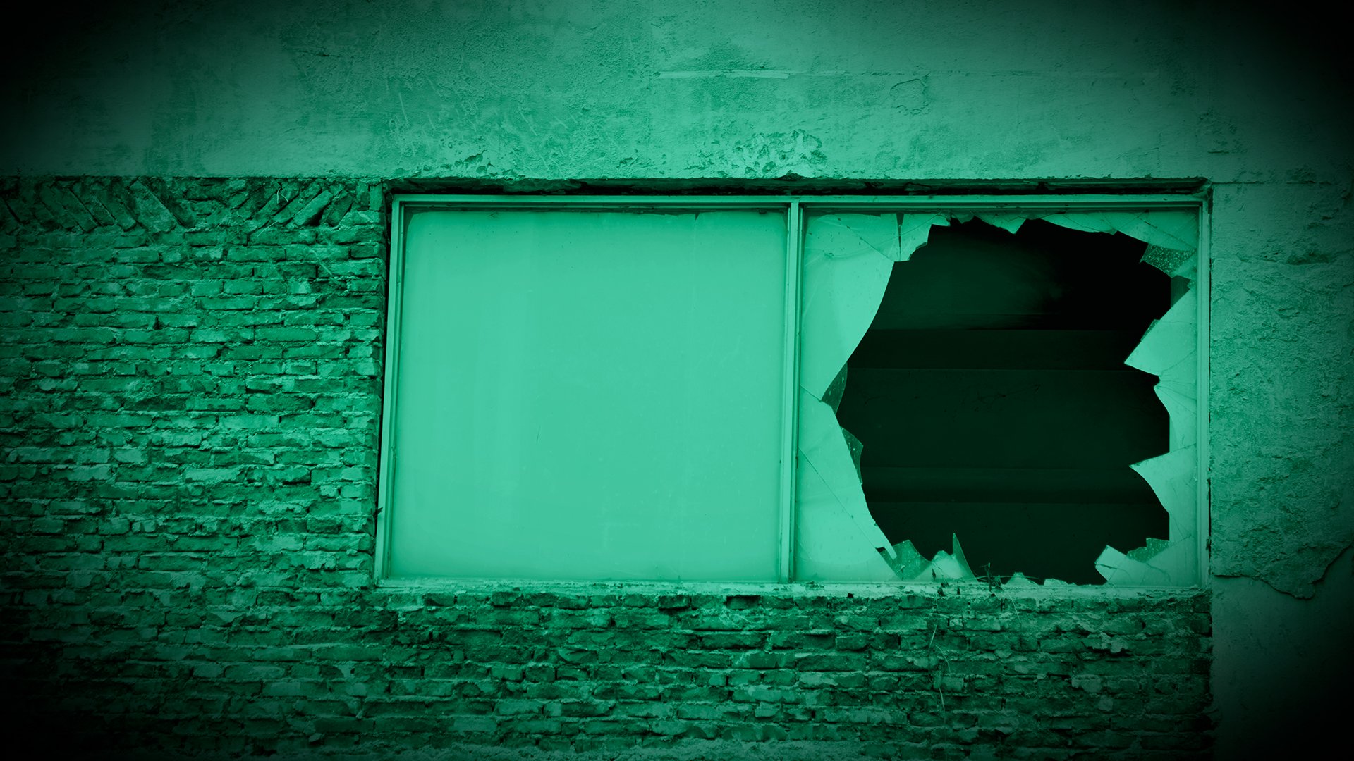 Uma janela alta tem seu vidro destruído. Há um filtro verde na imagem.