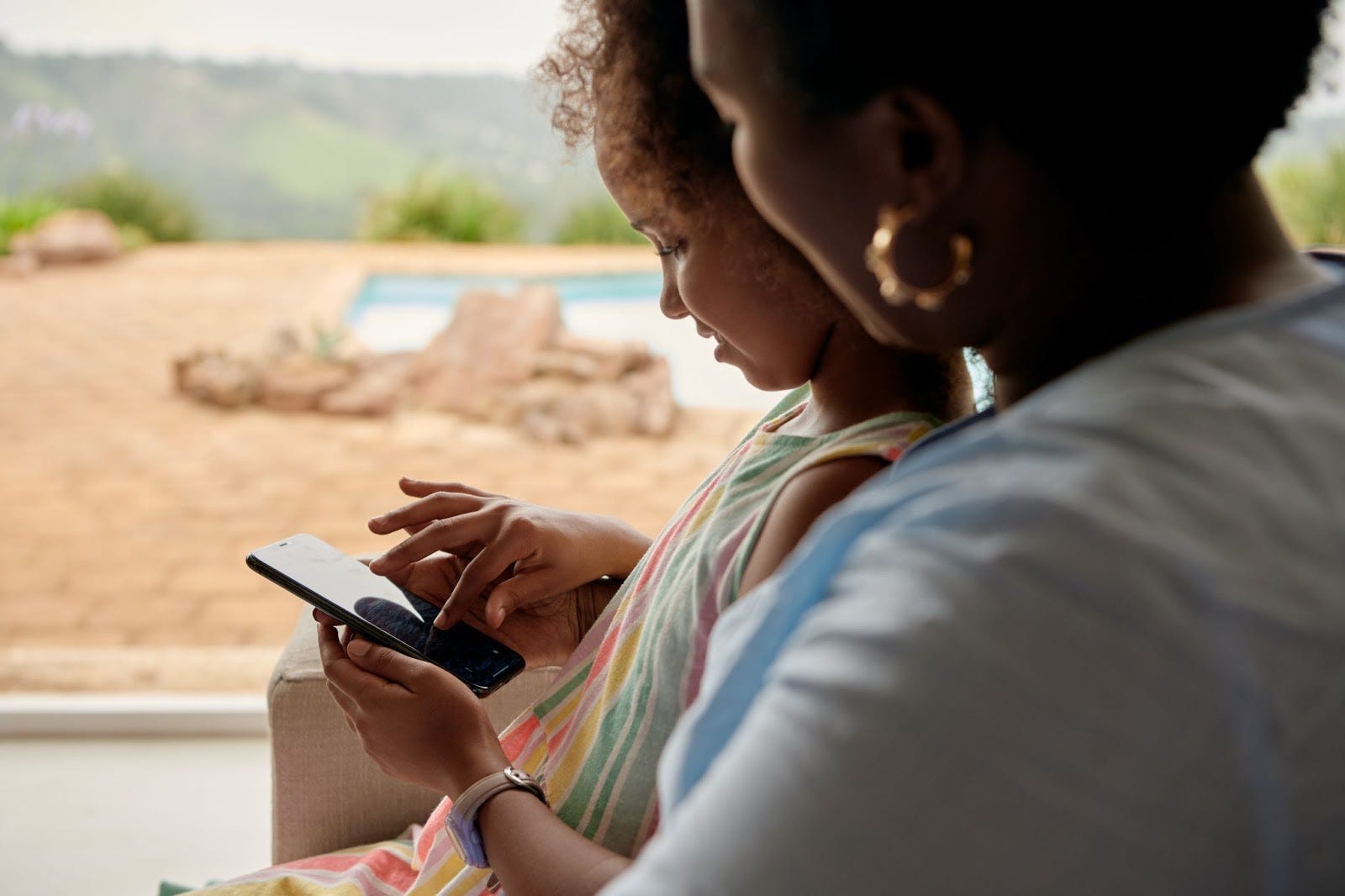 mother and daughter sitting on a chair, scrolling through their phone