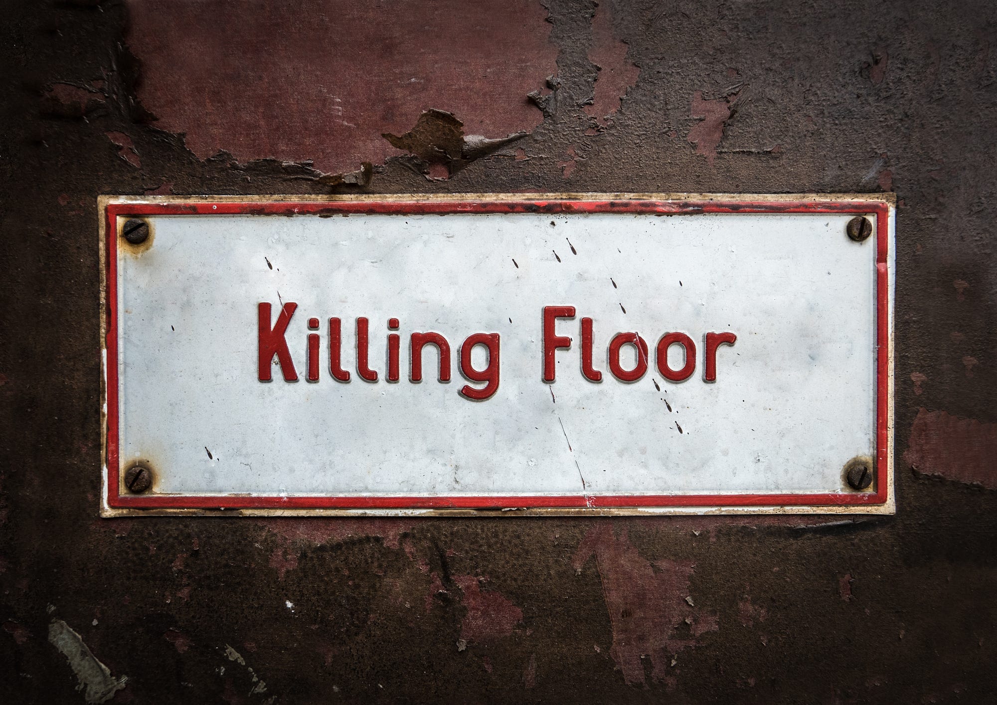 A white metal sign that reads “Killing Floor” in red lettering.