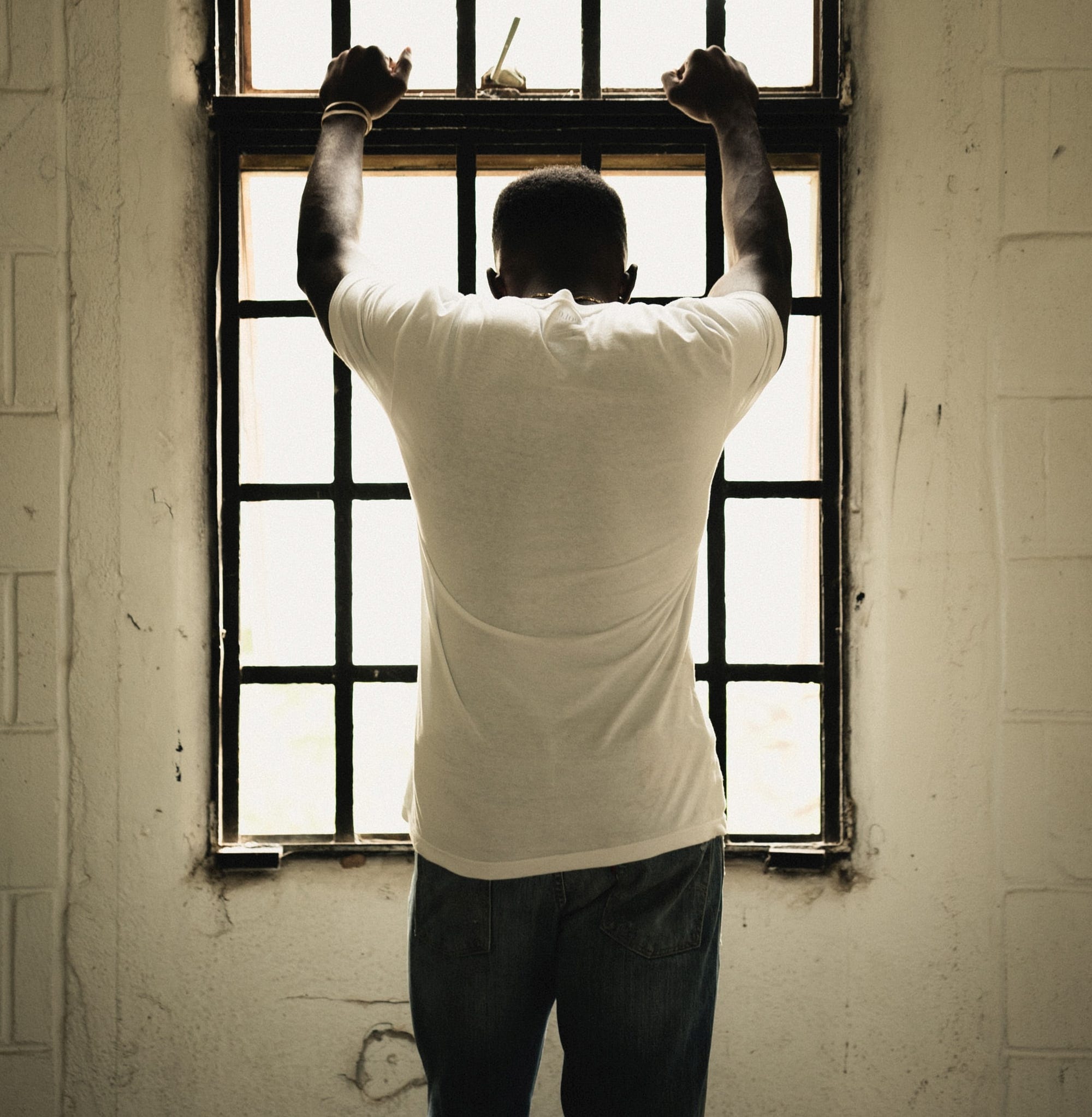 a sad man standing in front of a window