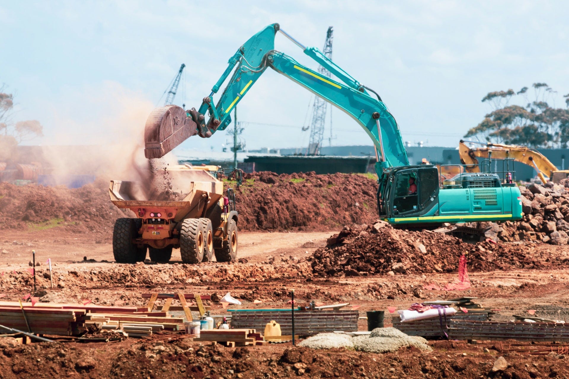 Big bulldozer throwing sand on a truck in the middle of a construction site
