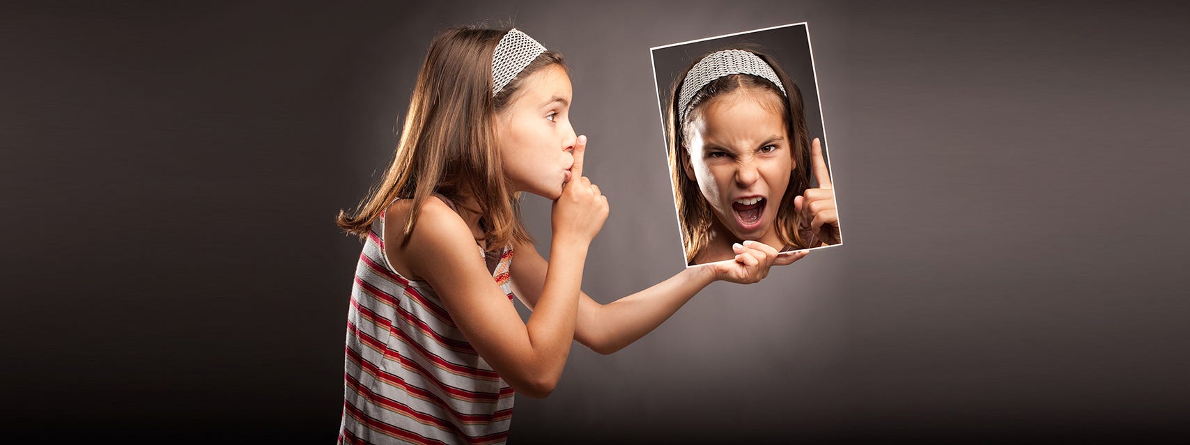 Young girl “shhhushing” a pciture of her angry self.