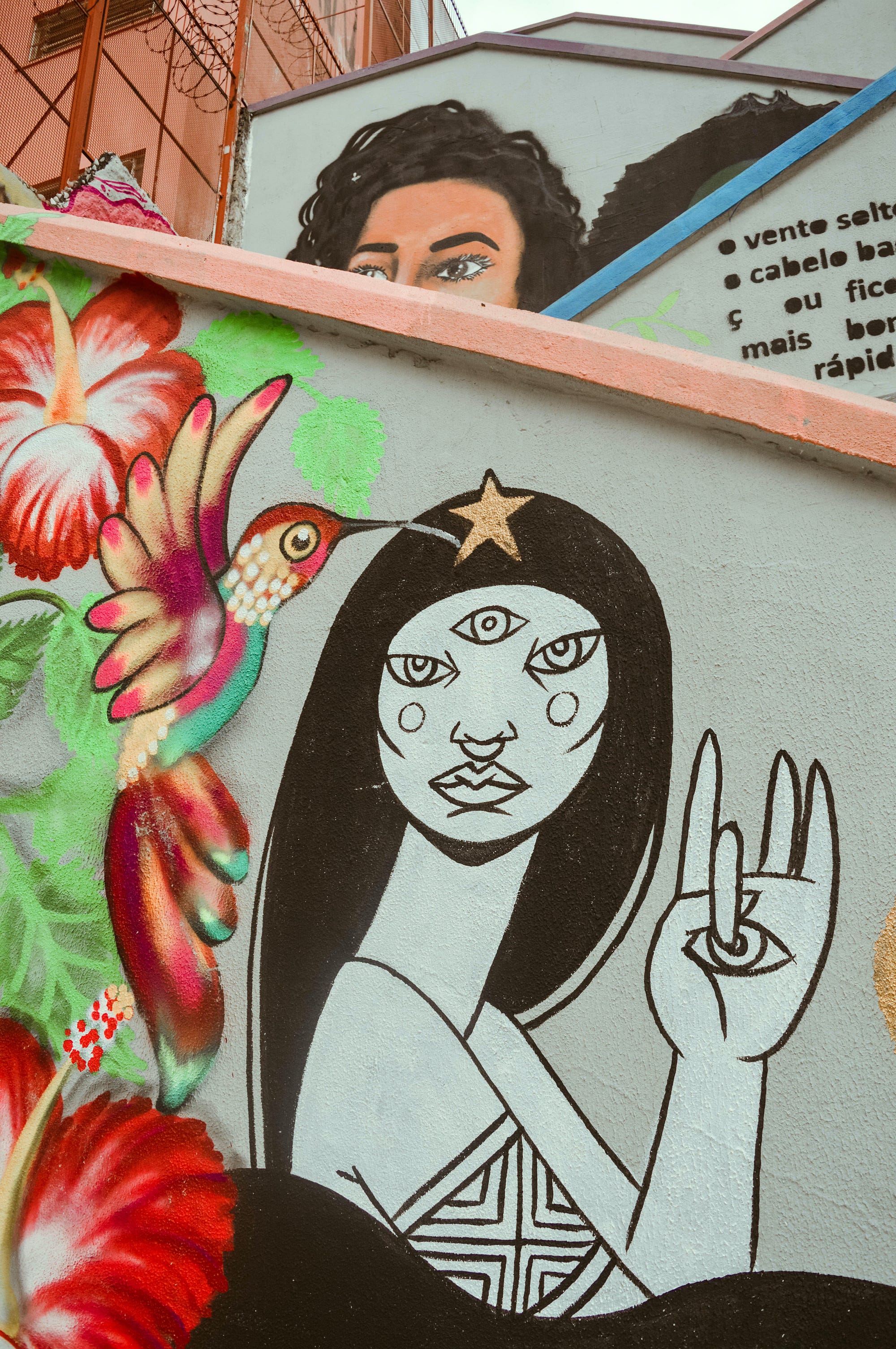 Street art in Sao Paulo of woman with three eyes and holding up a hand with an eye on the palm