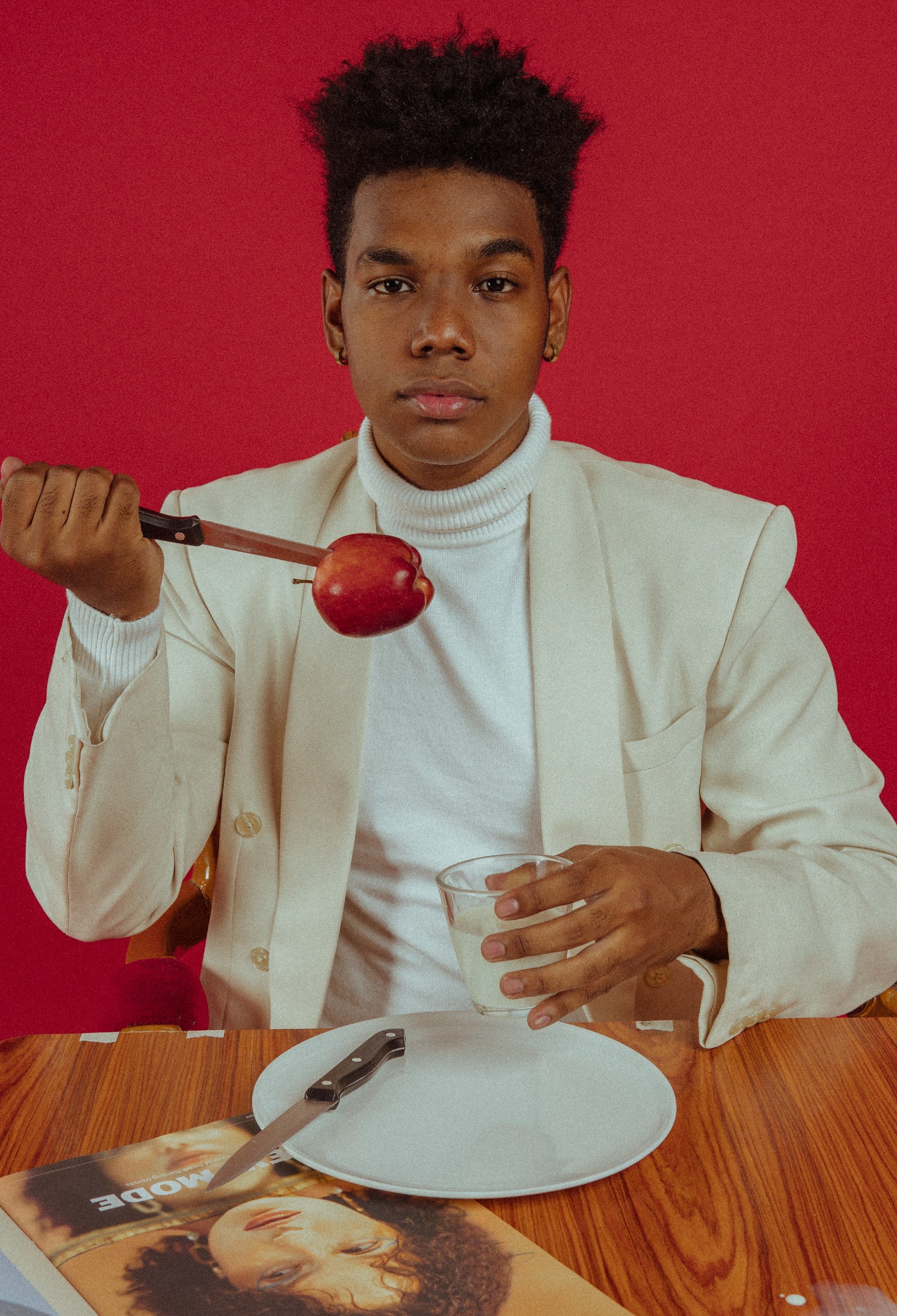 A person, holds a knife that stabbed an apple.