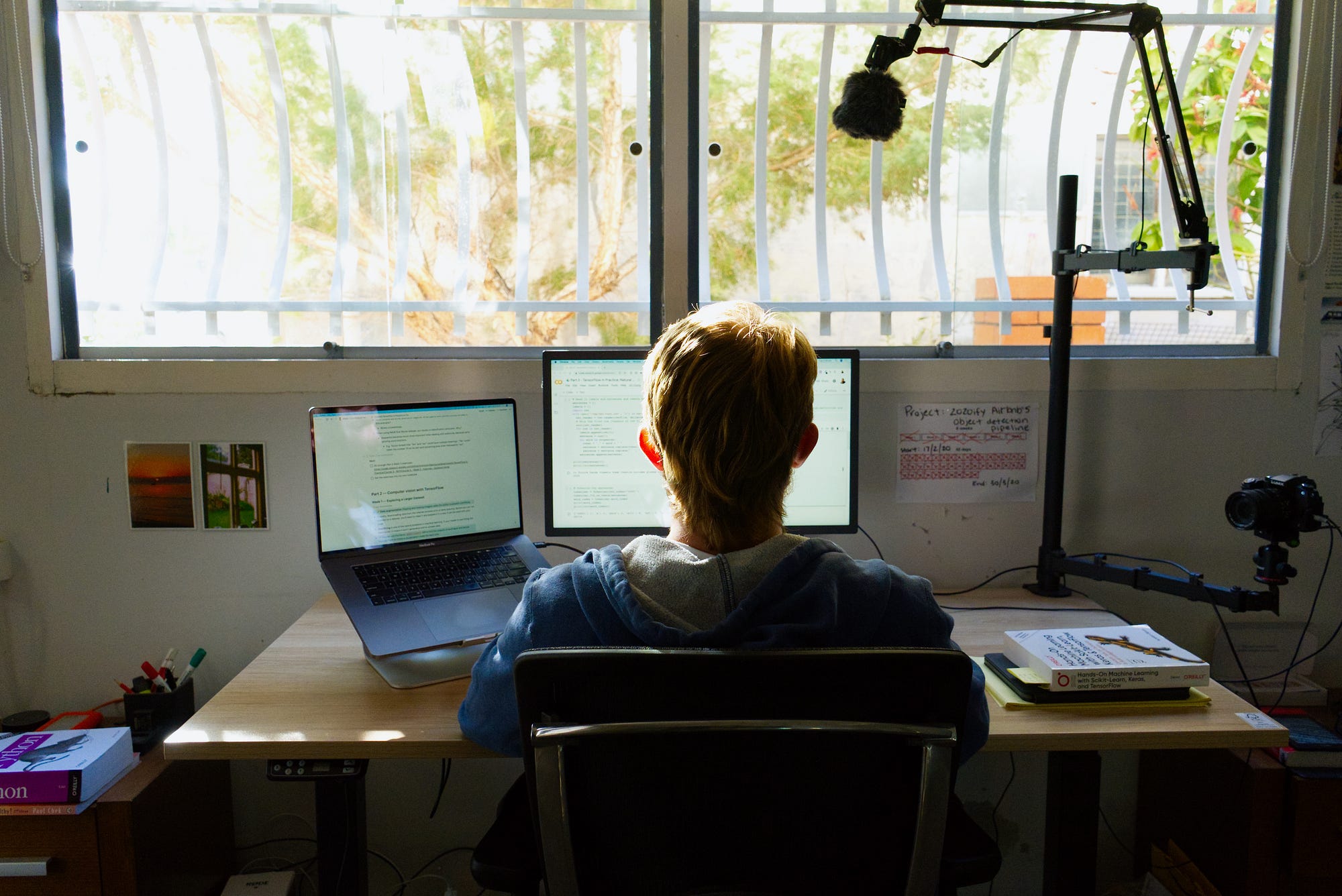 man with a mullet sitting at computer desk with camera on right and microphone over the top