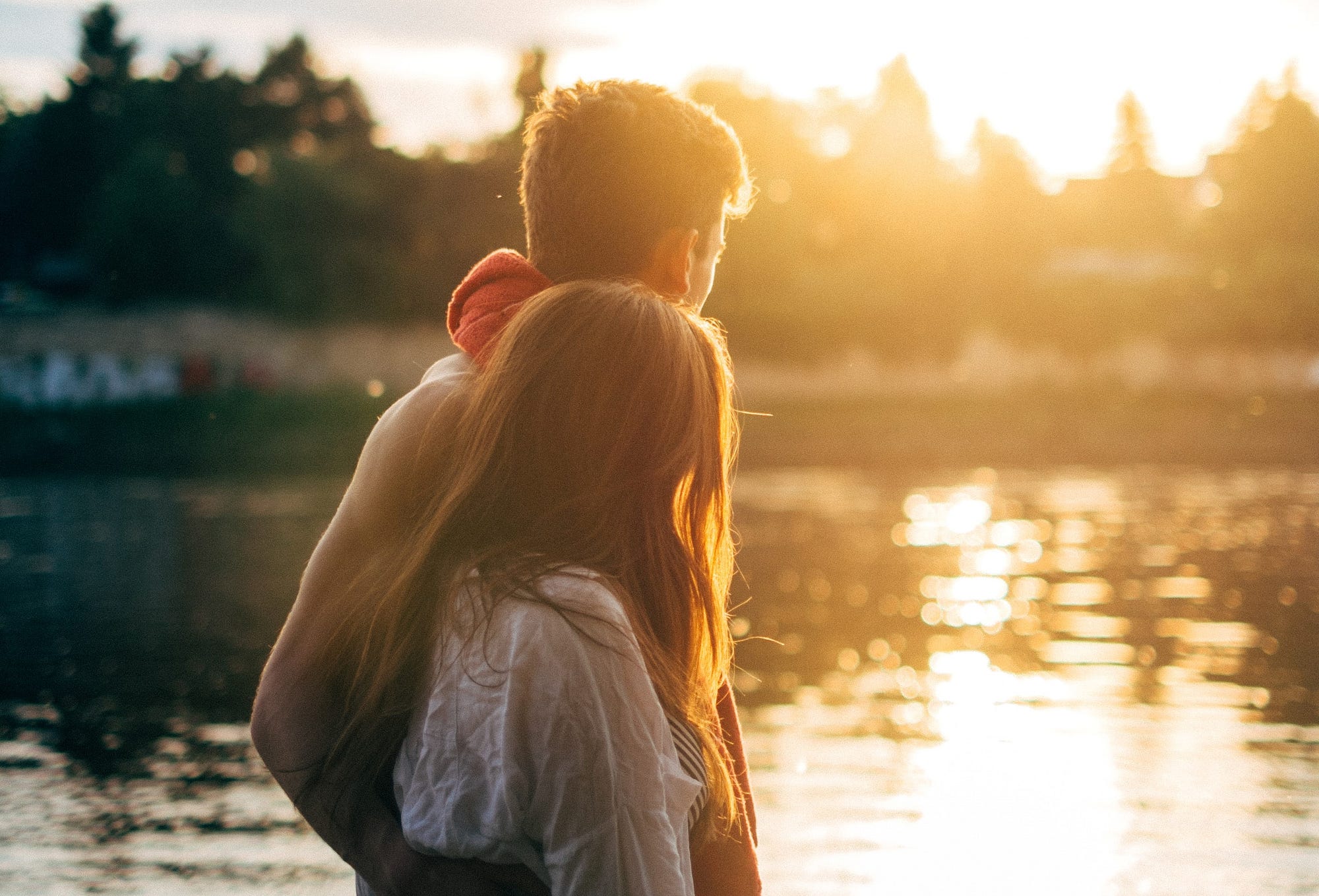 A young couple entwined, male and female, walking by a lake