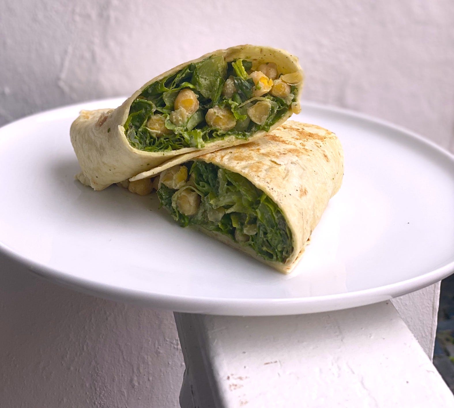 Chickpeas and lettuce shimmering with a creamy caesar dressing, stuffed into a large tortilla folded wrap-style.