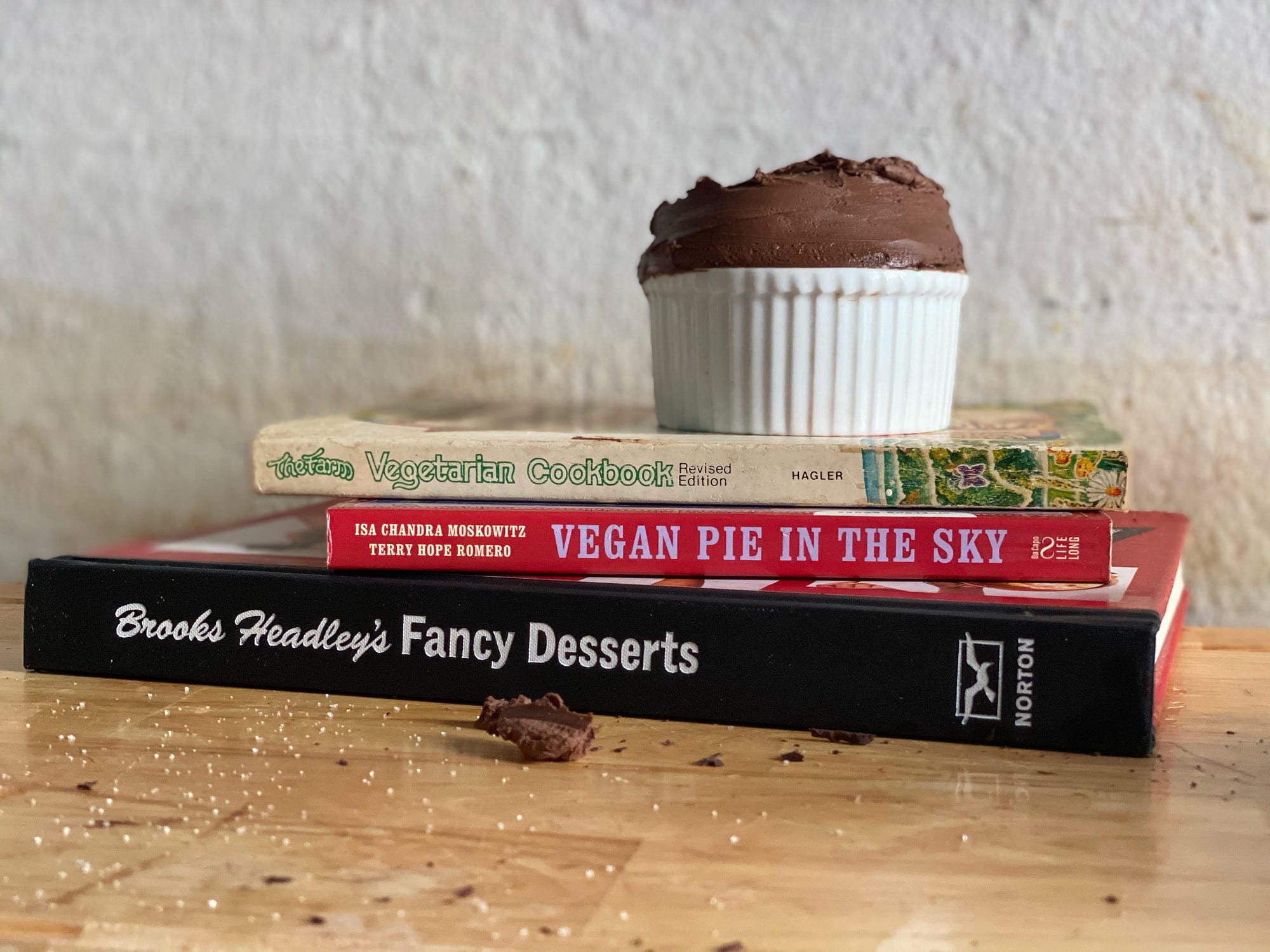 Ramekin of chocolate mousse on top of The Farm Vegetarian Cookbook, Vegan Pie in the Sky, Brooks Headley’s Fancy Desserts