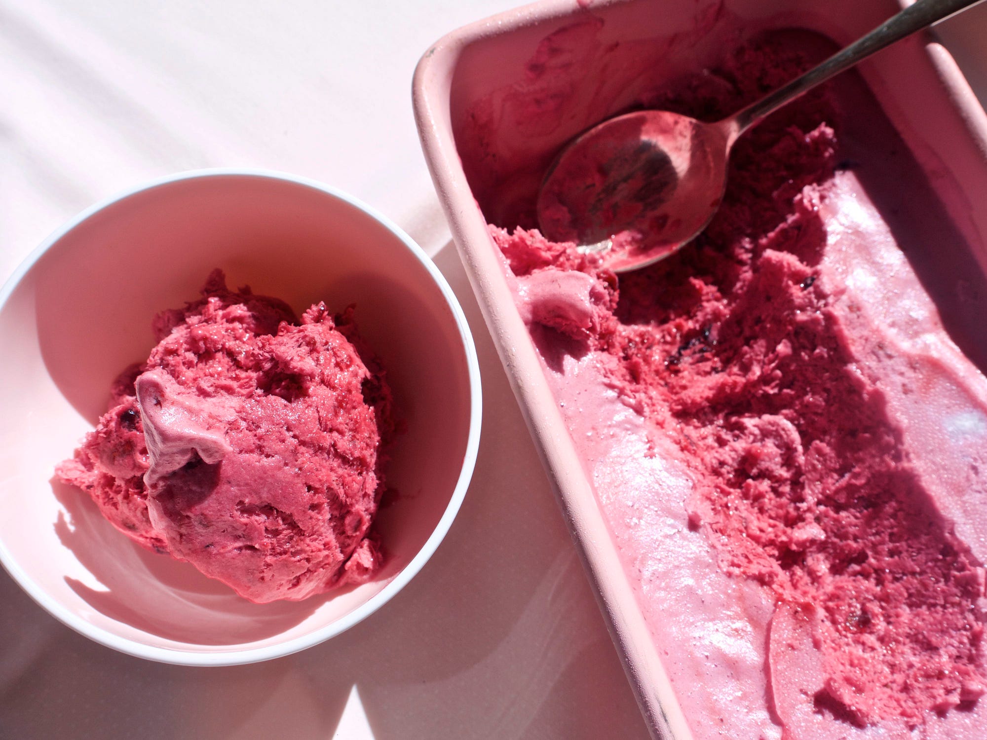 A fresh scoop of deep purple berry ice cream from a carton of the same rich looking ice cream.